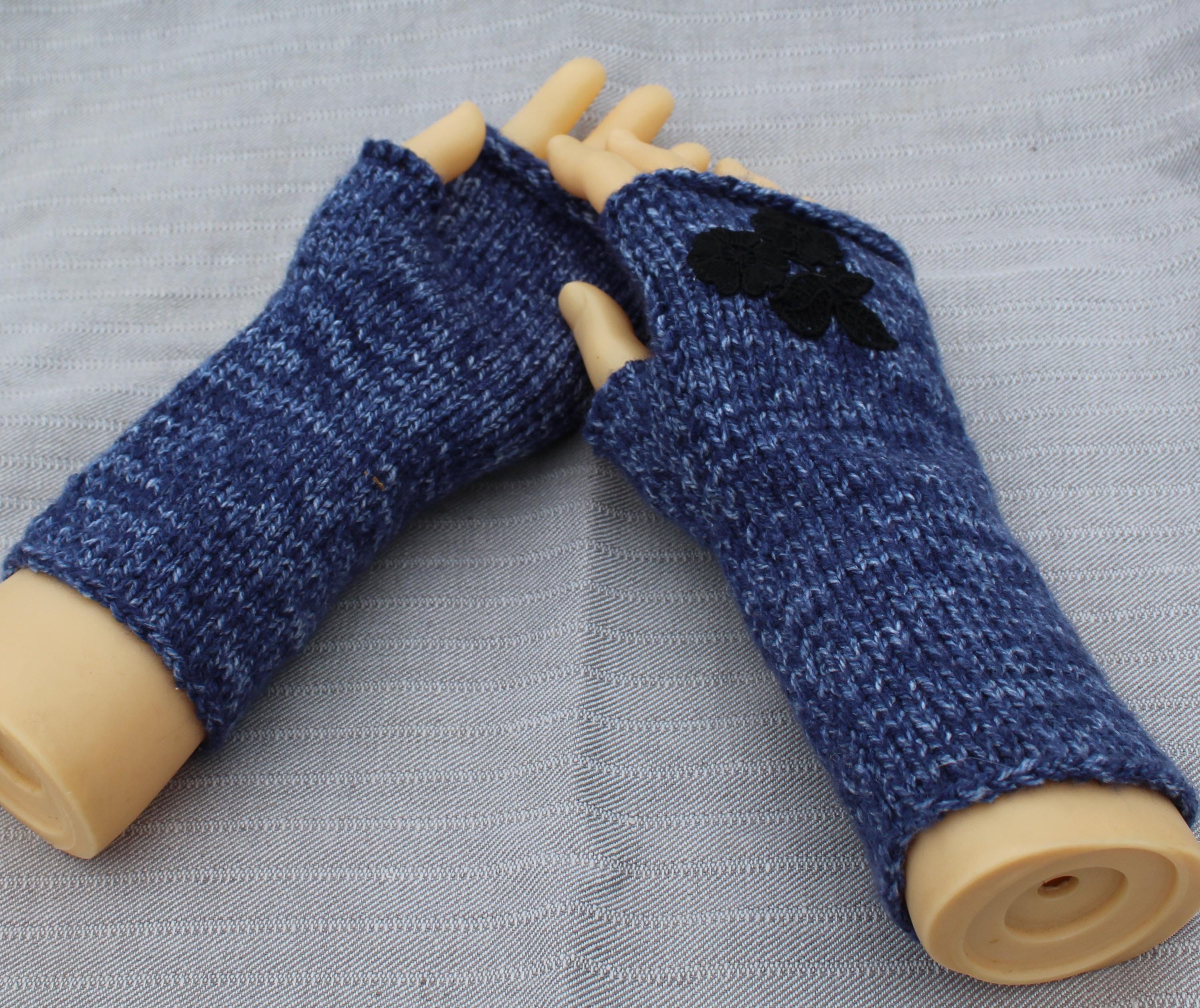 Blue knitted arm warmers on a mannequin arm against a gray background