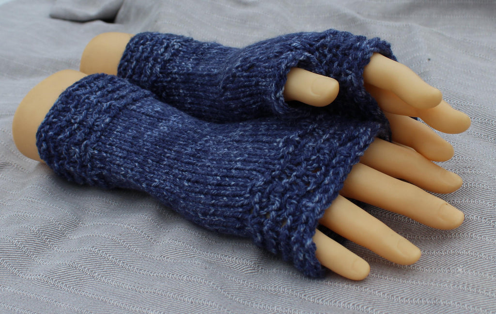 Blue knitted fingerless gloves on a mannequin hand against a gray background