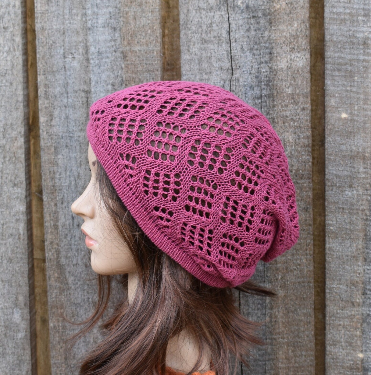 Pink knitted hat worn by a mannequin against a wooden background