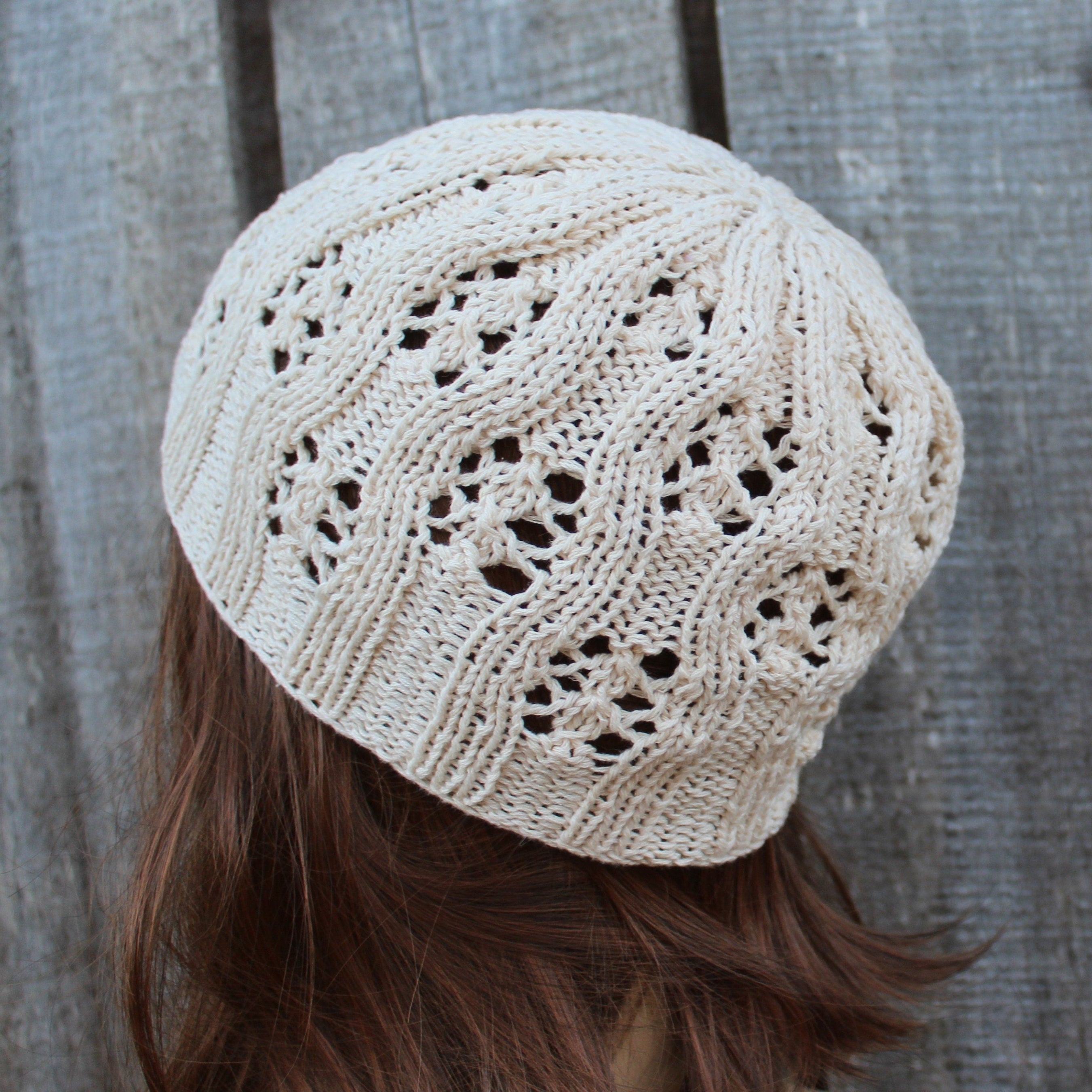 Beige knitted beanie worn by a person with brown hair against a wooden background
