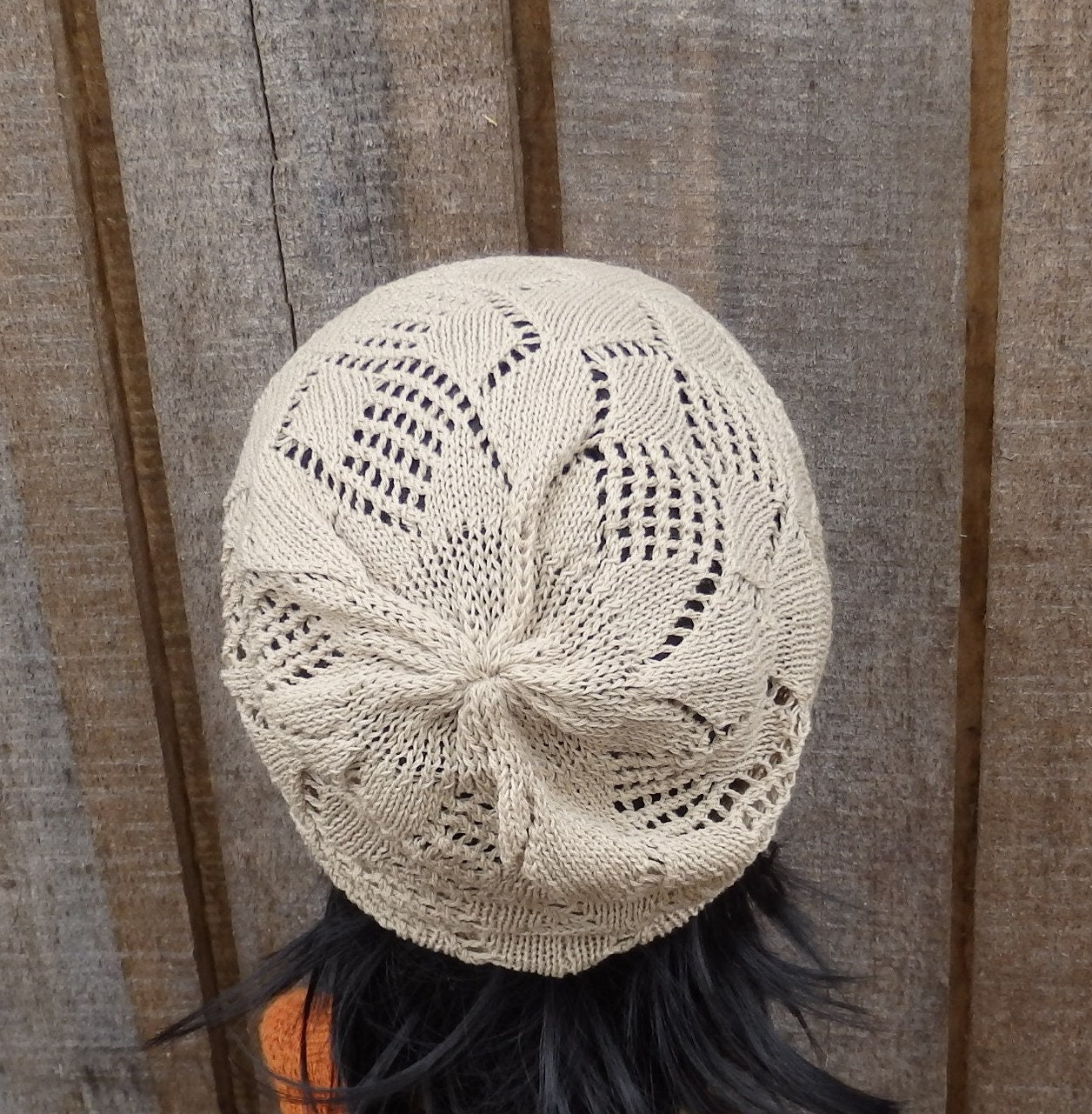 Knitted beige hat on a person against a wooden background