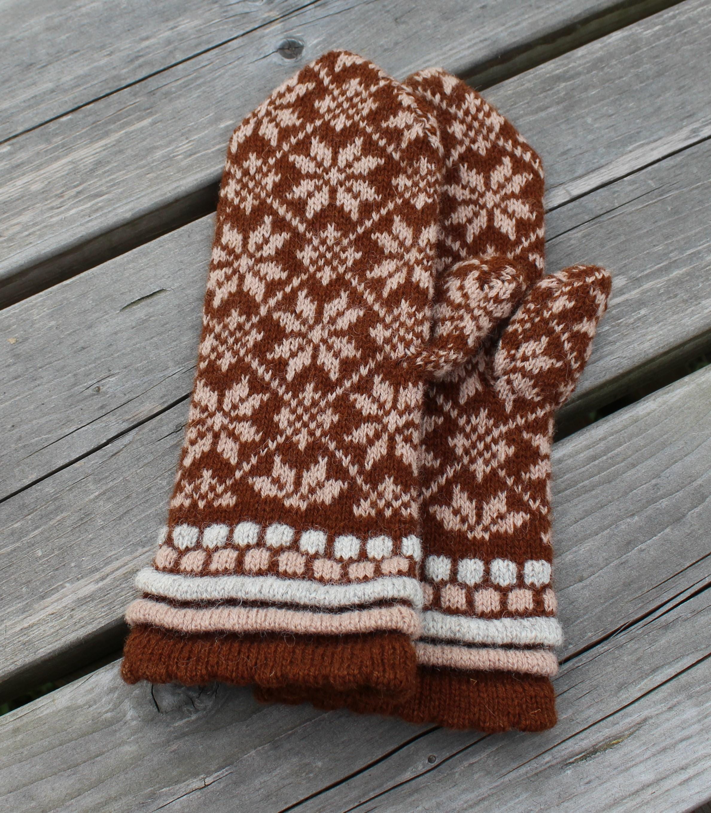 Pair of brown and beige patterned mittens on a wooden surface