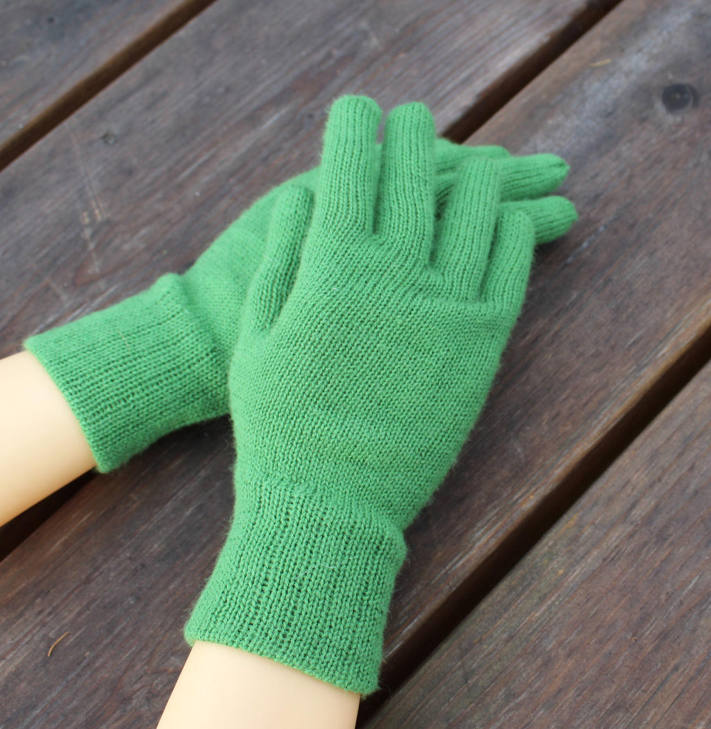 Green knitted gloves on a wooden surface