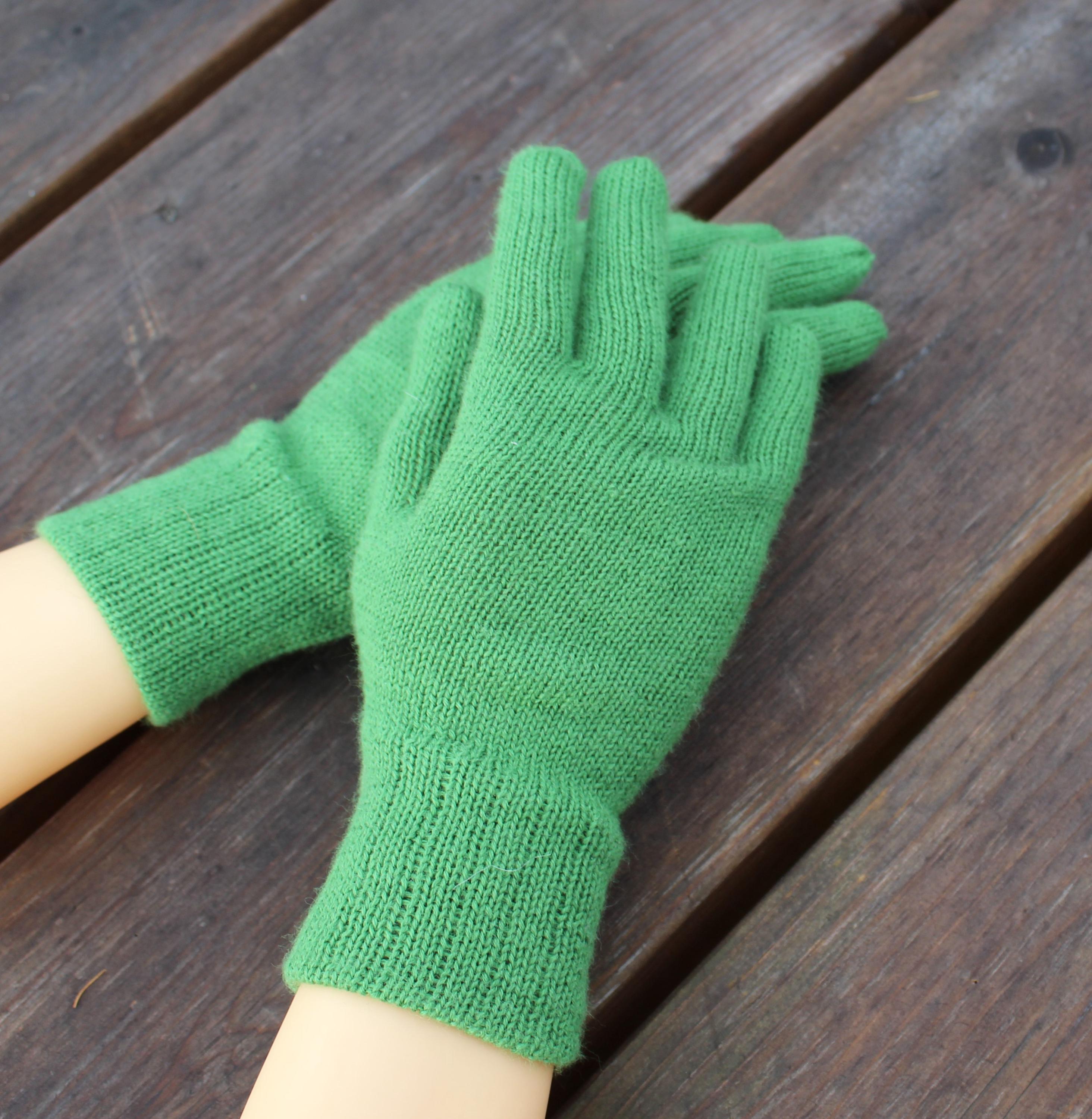 Green knitted gloves on a wooden surface