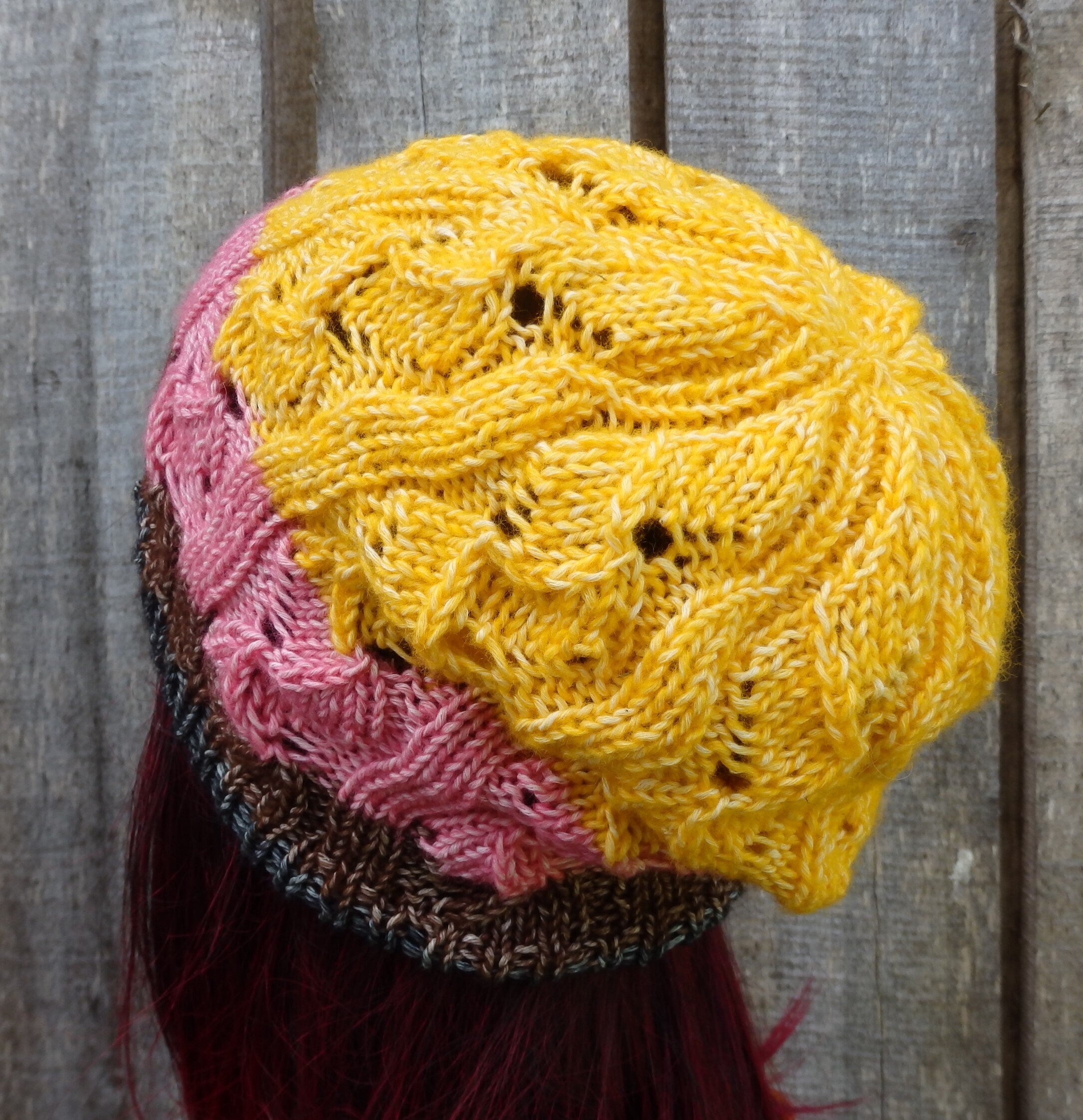 Stack of colorful knitted hats on a wooden surface