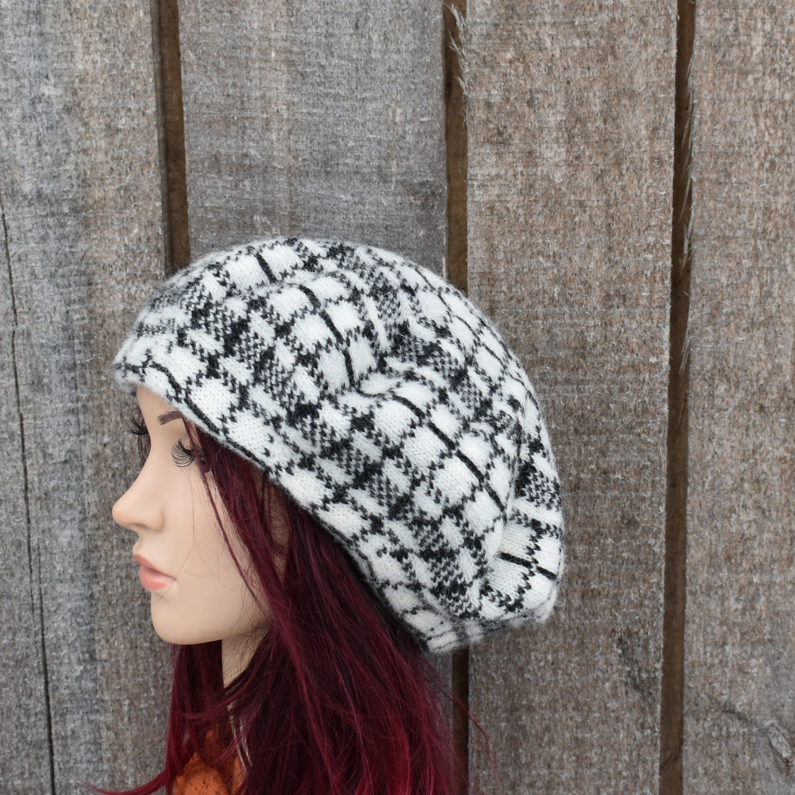 Mannequin head wearing a black and white checkered hat against a wooden background