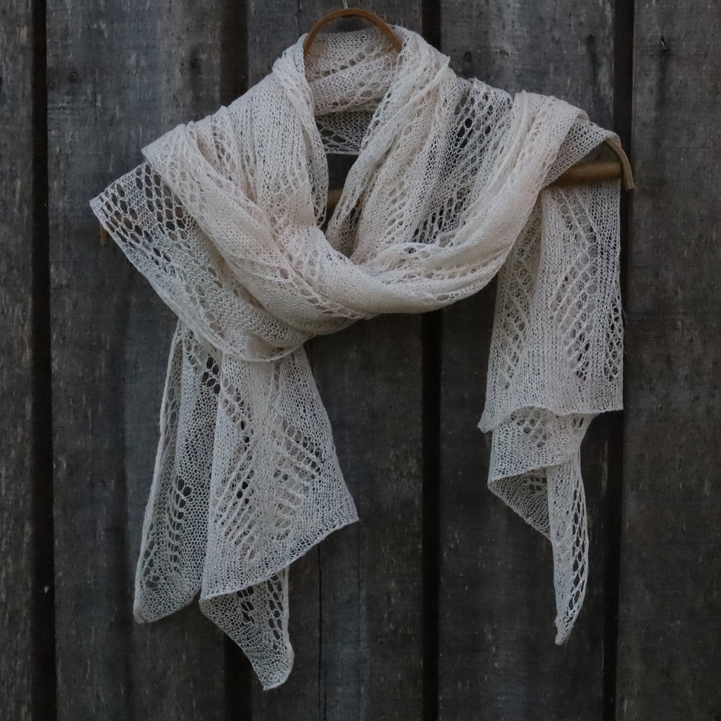 White lace scarf hanging on a wooden hanger against a dark wooden background