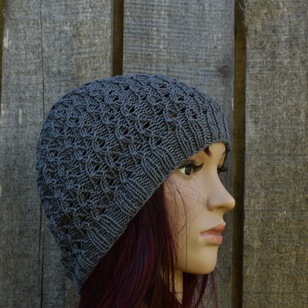 Mannequin head wearing a gray knit beanie against a wooden panel background