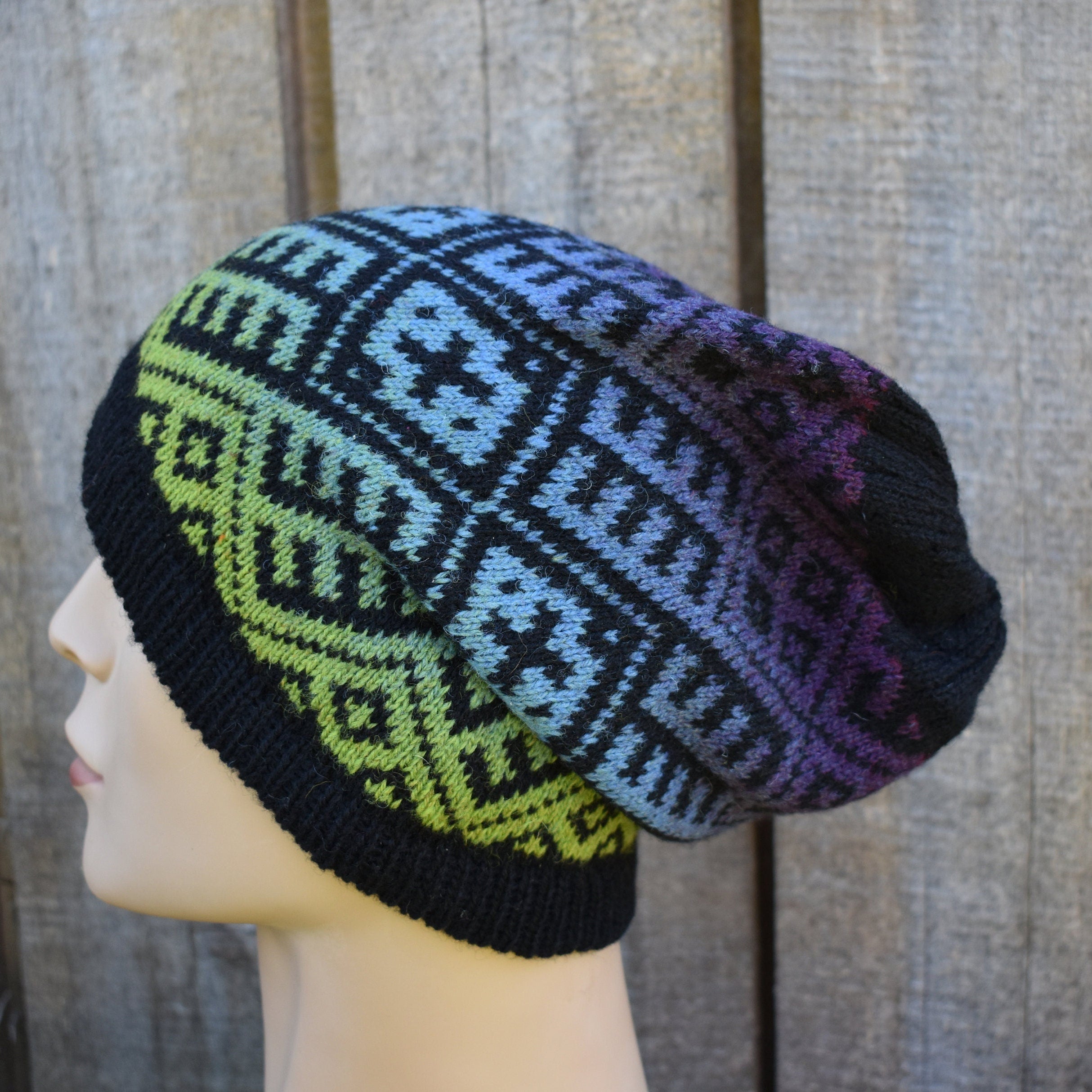 Knitted beanie with geometric pattern on a mannequin head against a wooden background