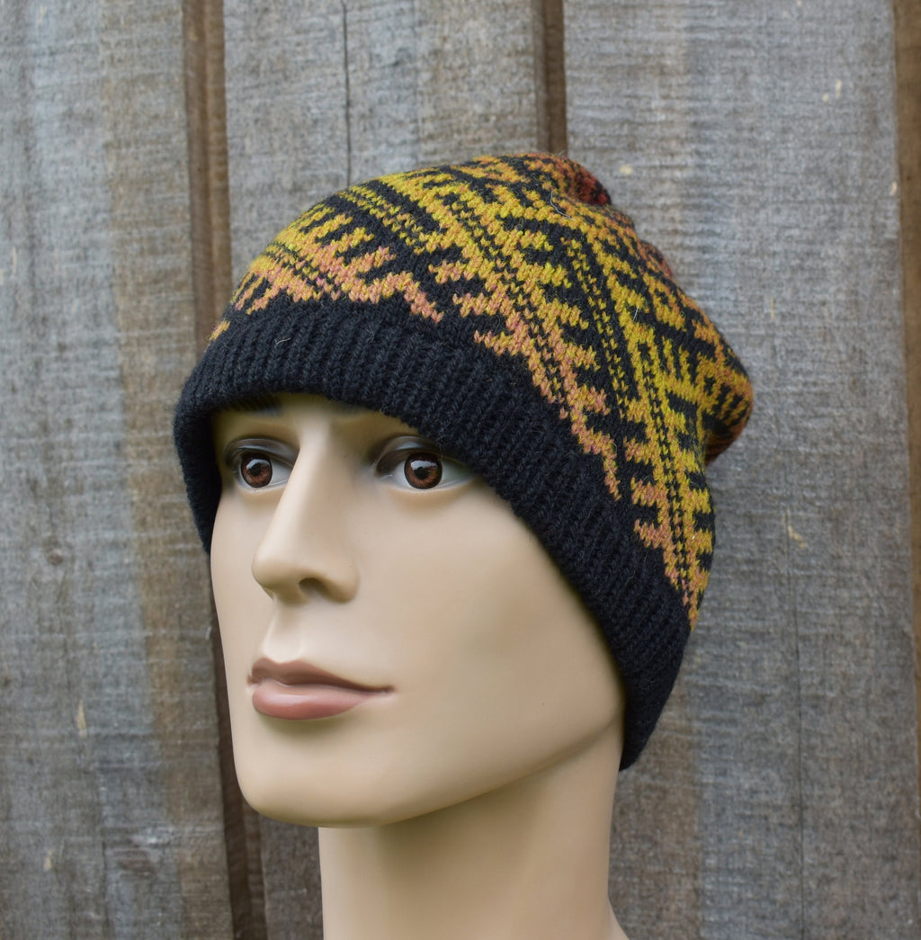 Knitted beanie with black and yellow pattern on a mannequin head against a wooden background