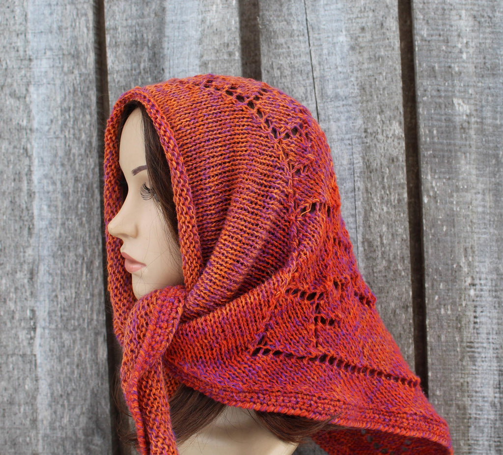 Mannequin wearing a orange knitted head wrap against a wooden background
