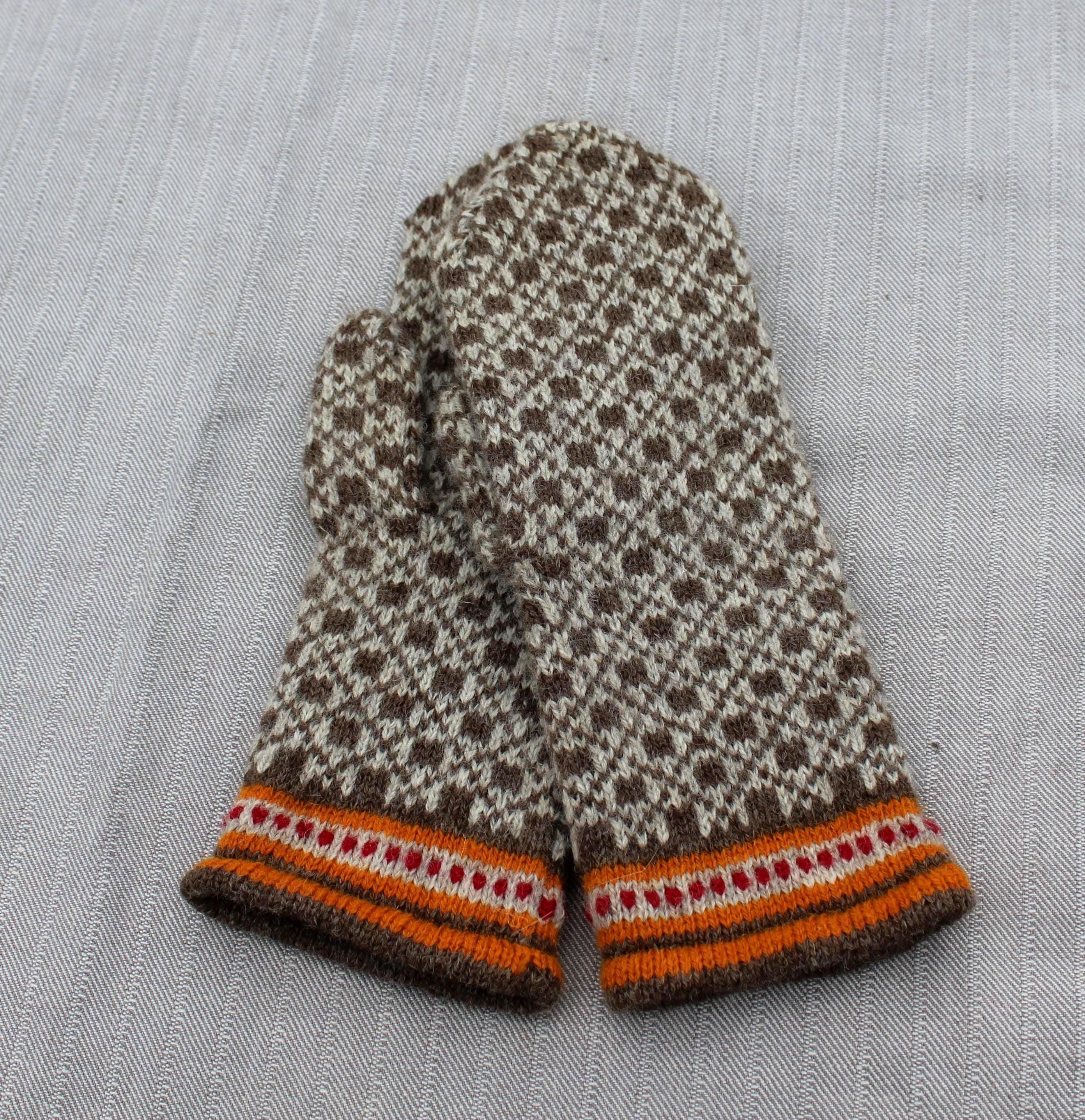 Pair of knitted mittens with a pattern on a light gray fabric background