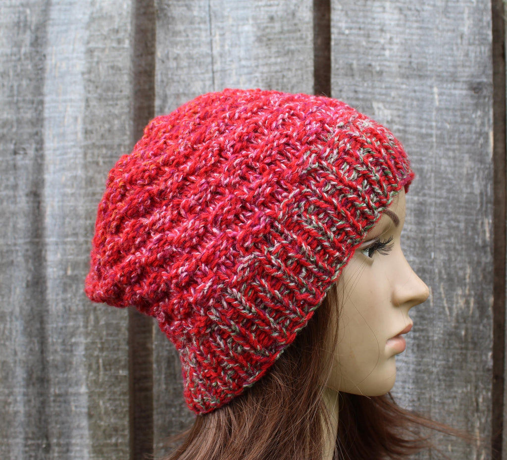 Red knitted beanie on a mannequin head against a wooden background