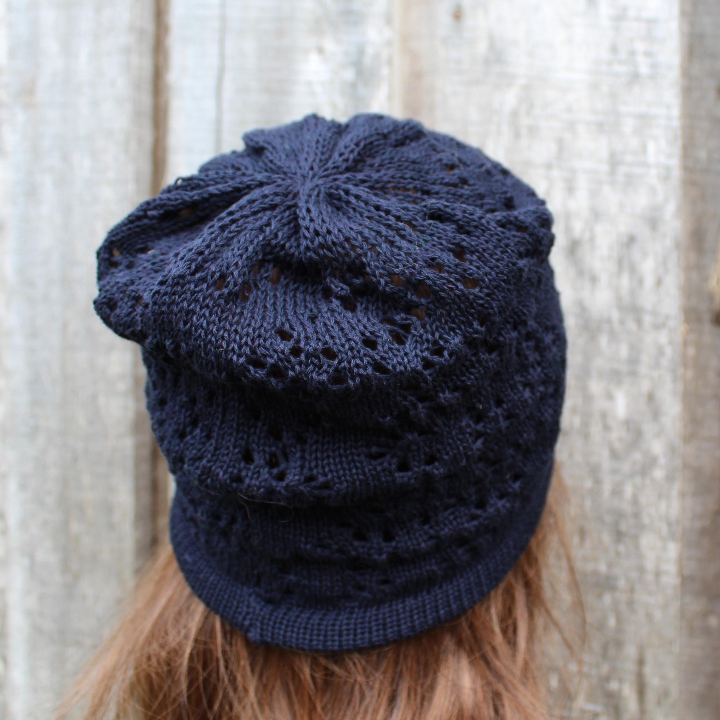 Navy blue knitted beanie on a person with a neutral background