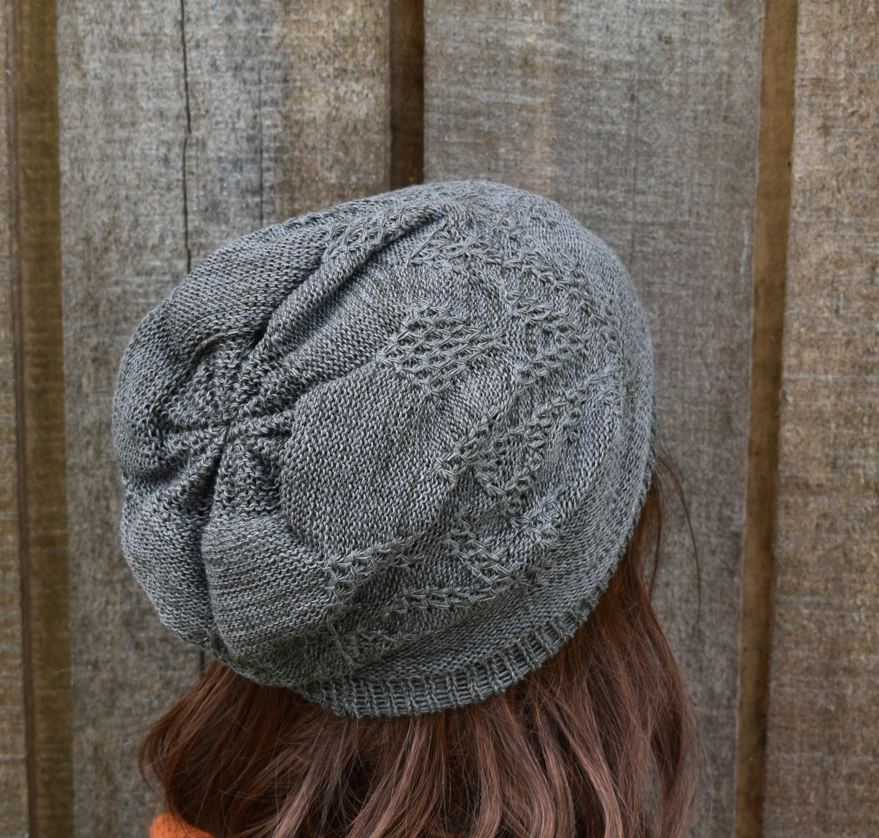 Gray knit hat worn by a person with a wooden background