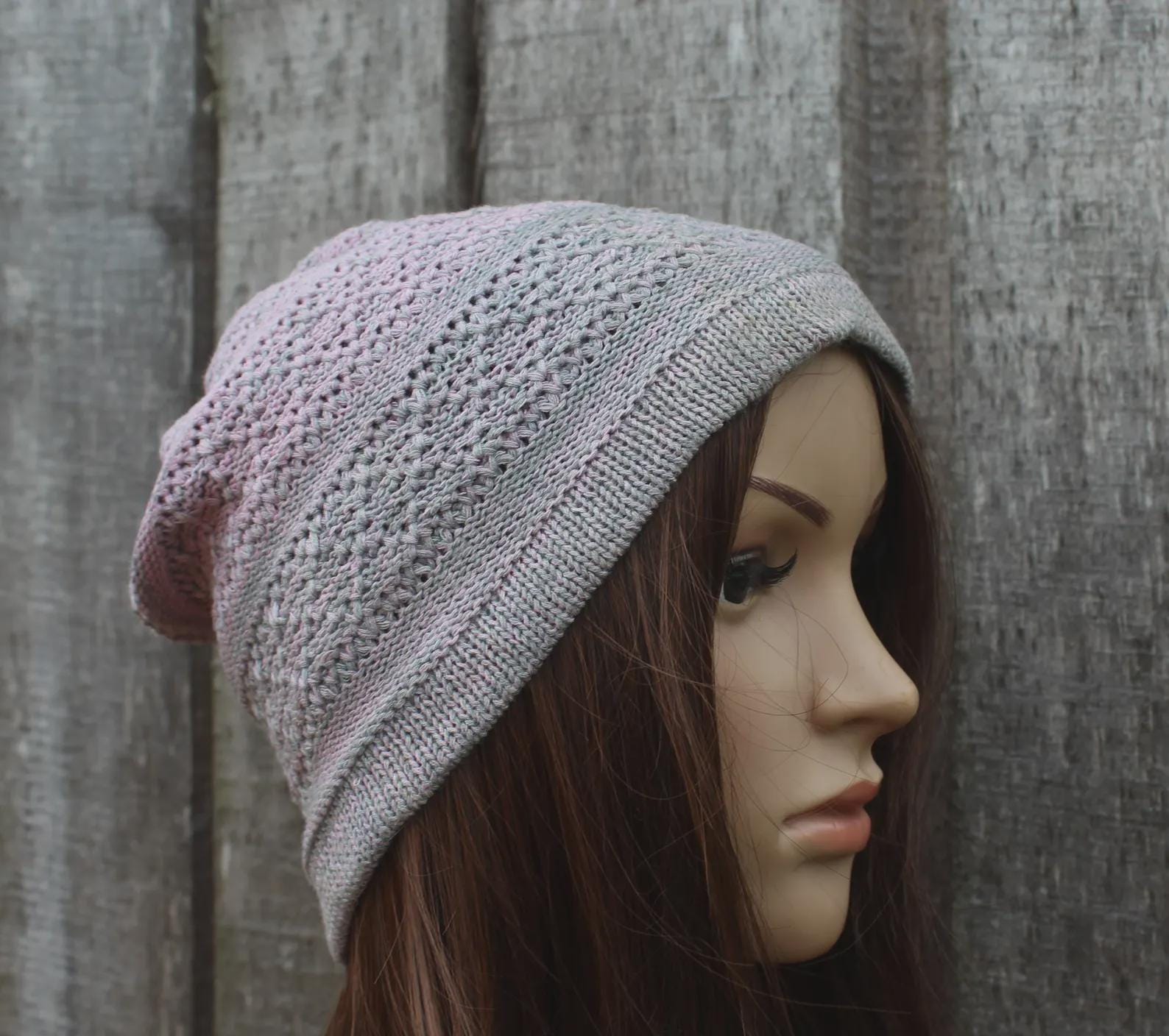 Mannequin head wearing a textured gray knit beanie against a wooden background