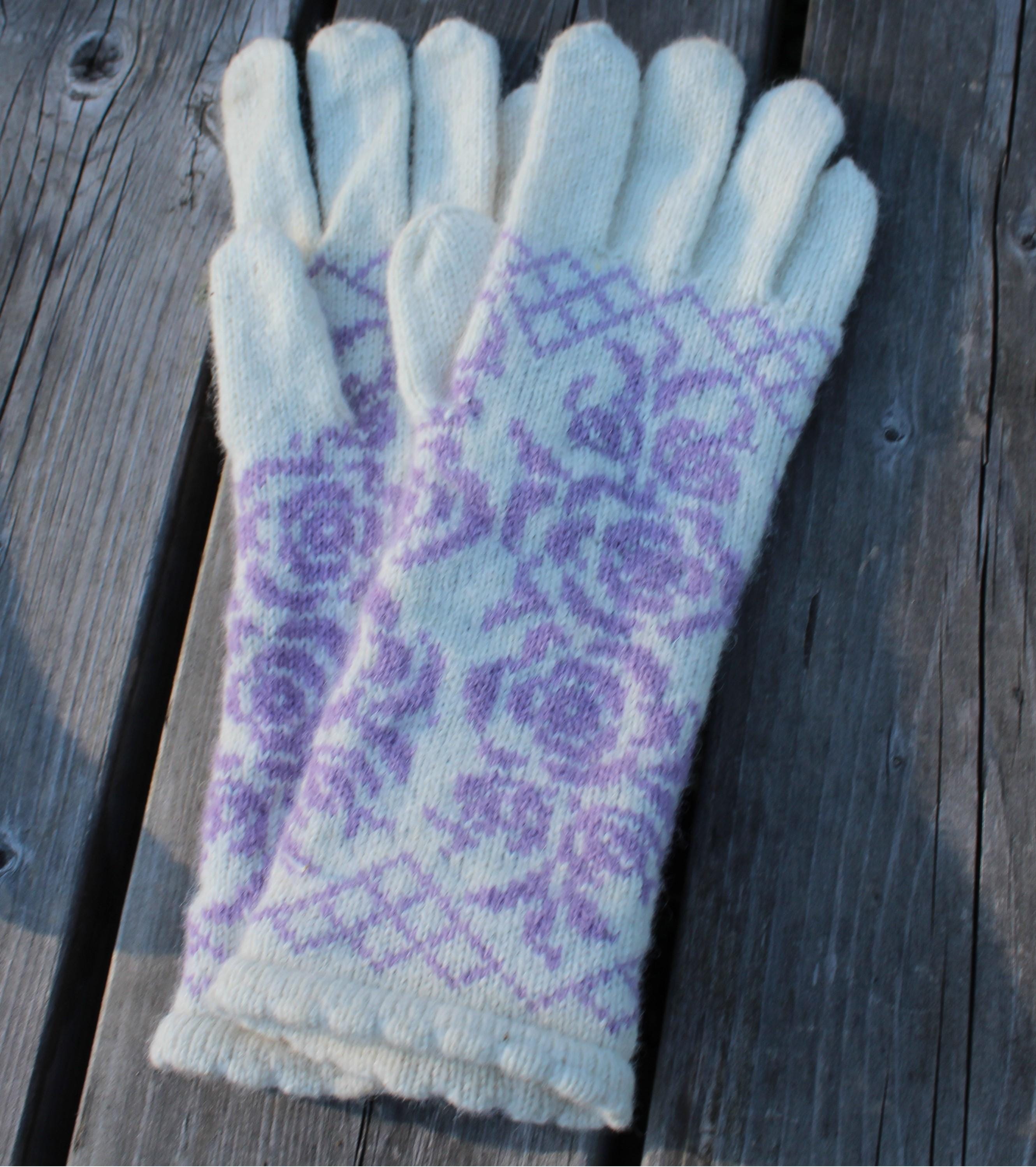 Pair of light blue gloves with purple floral pattern on a wooden surface