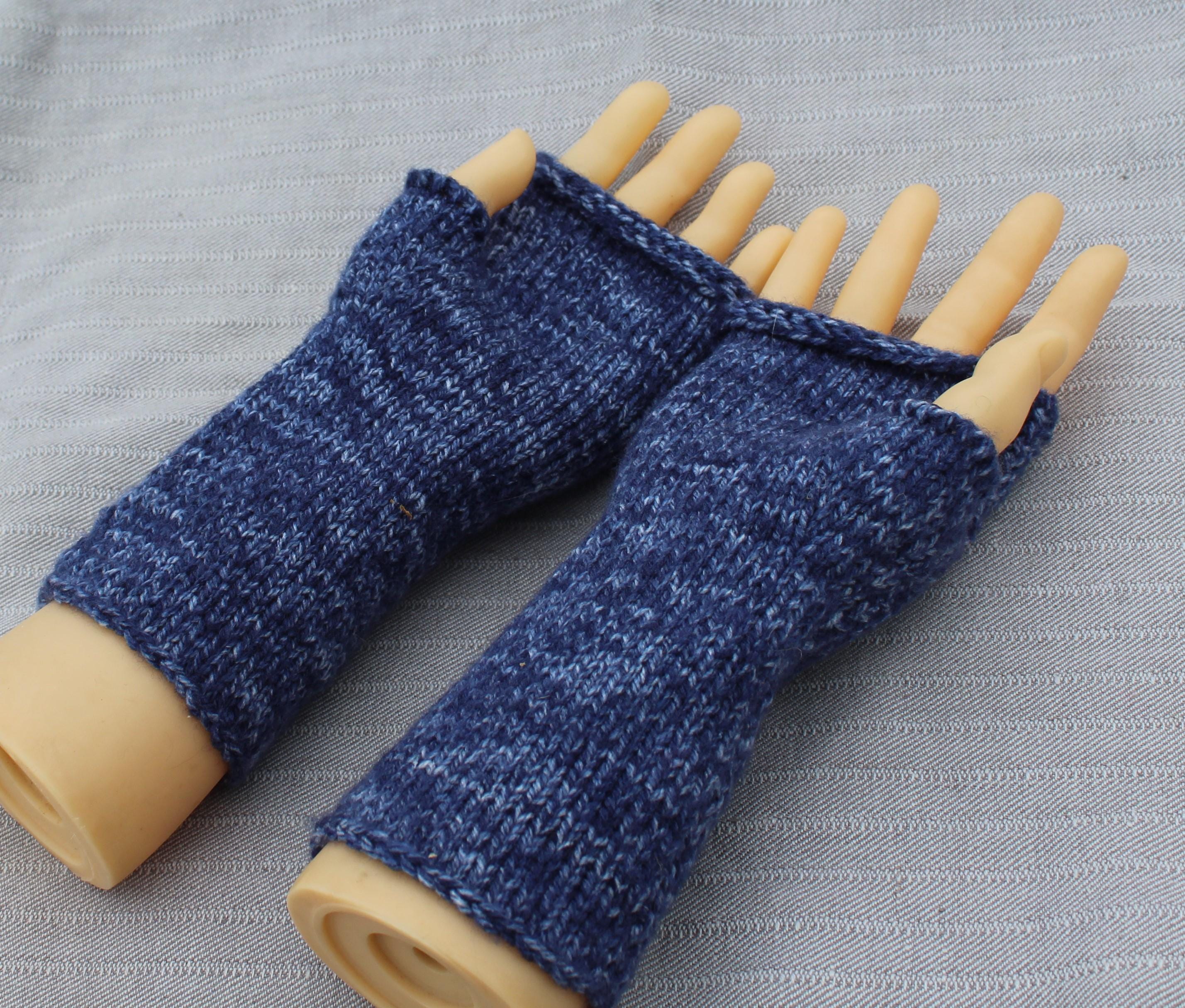Blue knitted fingerless gloves on a mannequin hand against a gray background