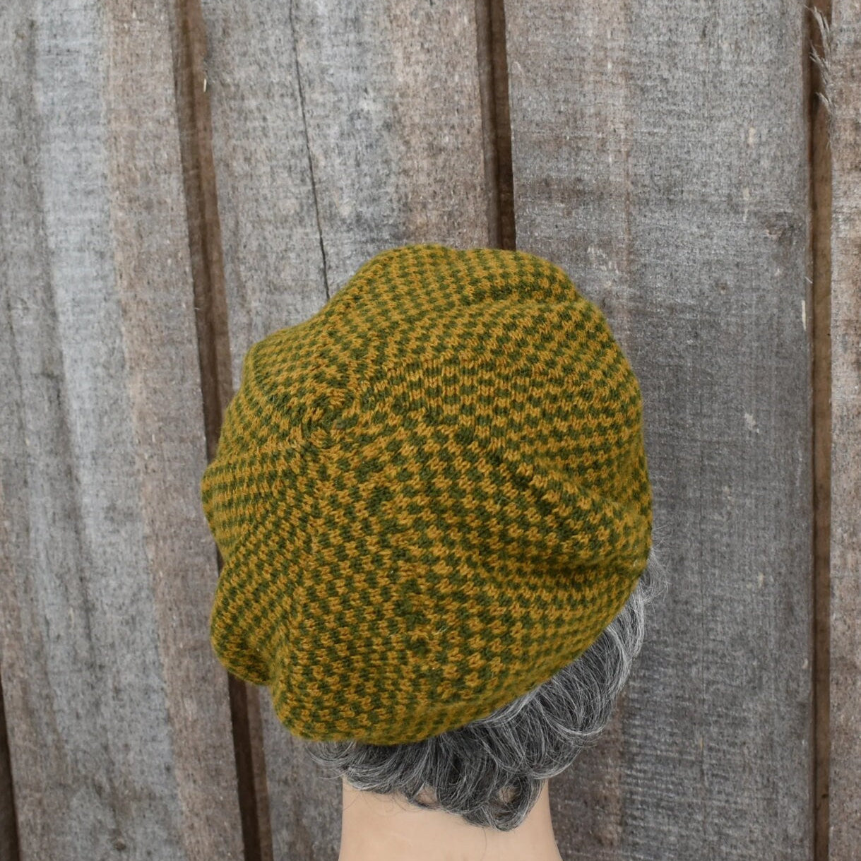 Green and brown checkered knitted hat on a wooden surface