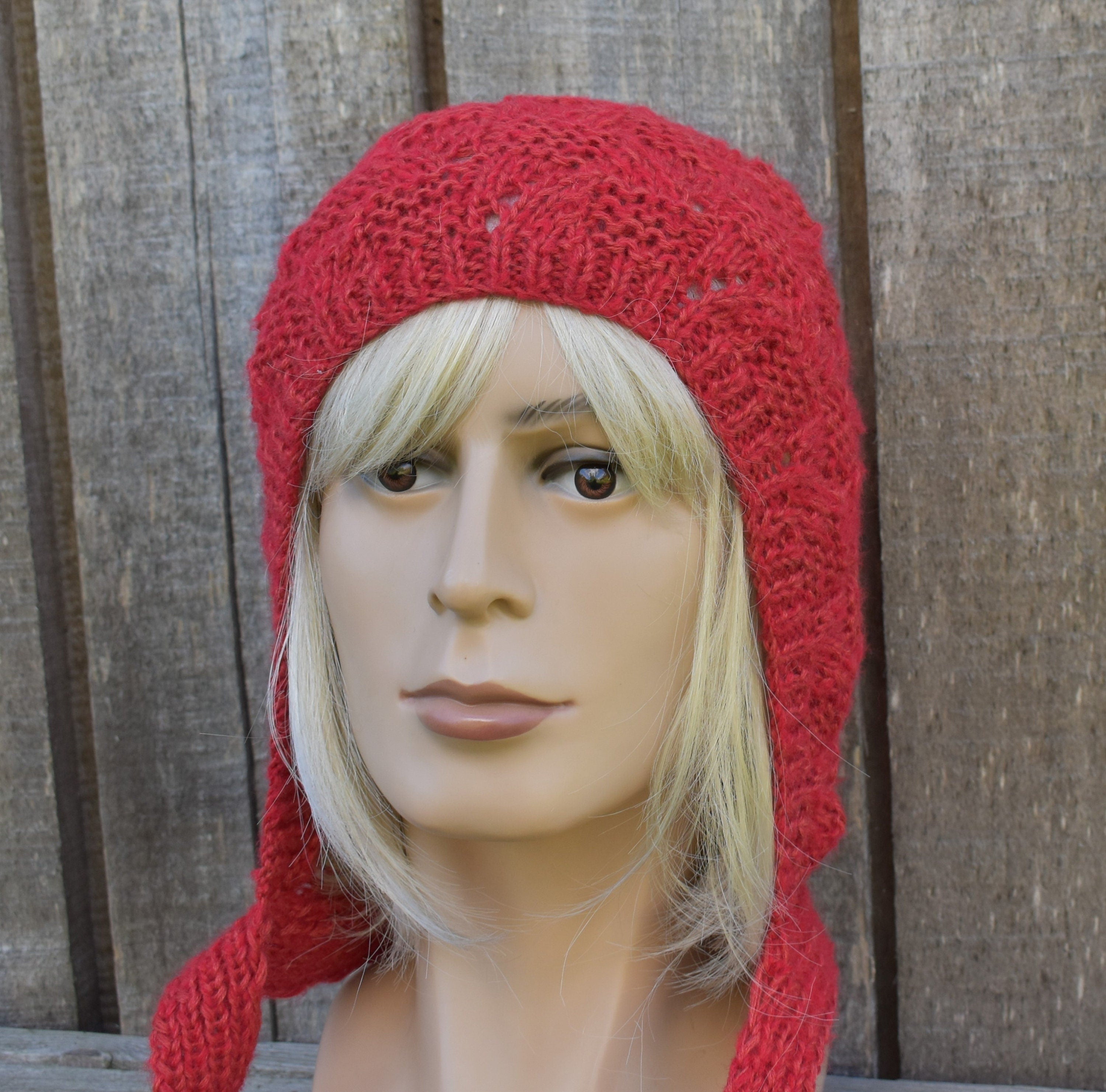Red knitted hat on a mannequin head against a wooden background
