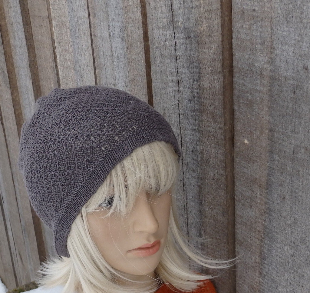 Mannequin head wearing a knitted gray beanie against a wooden fence background