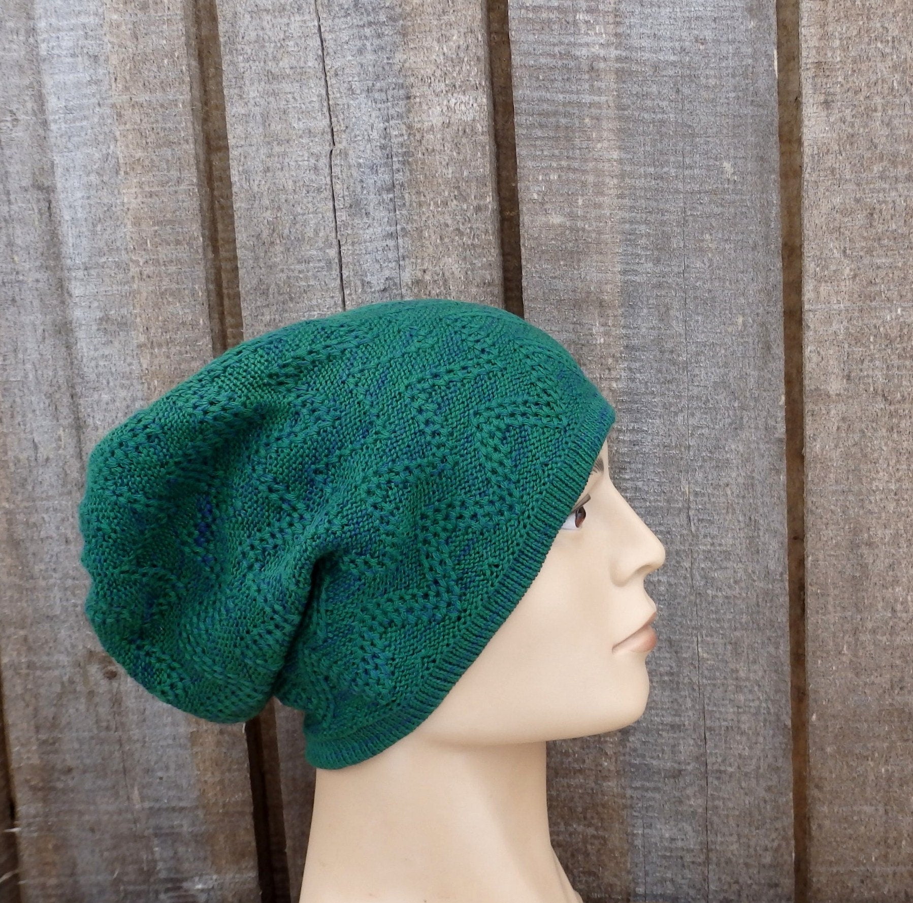 Green knitted beanie on a mannequin head against a wooden background