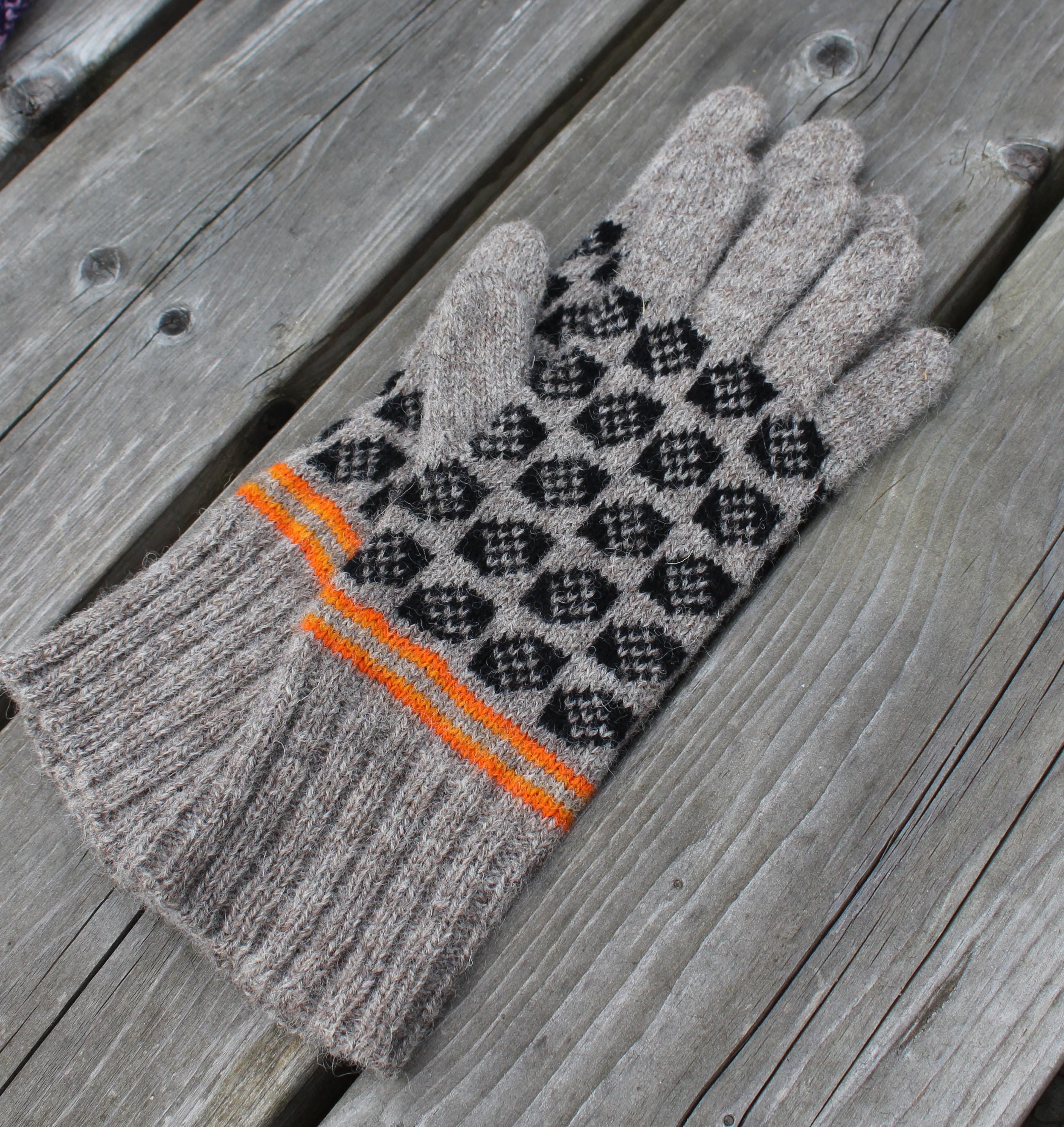 Gray glove with black pattern and orange strip on a wooden surface