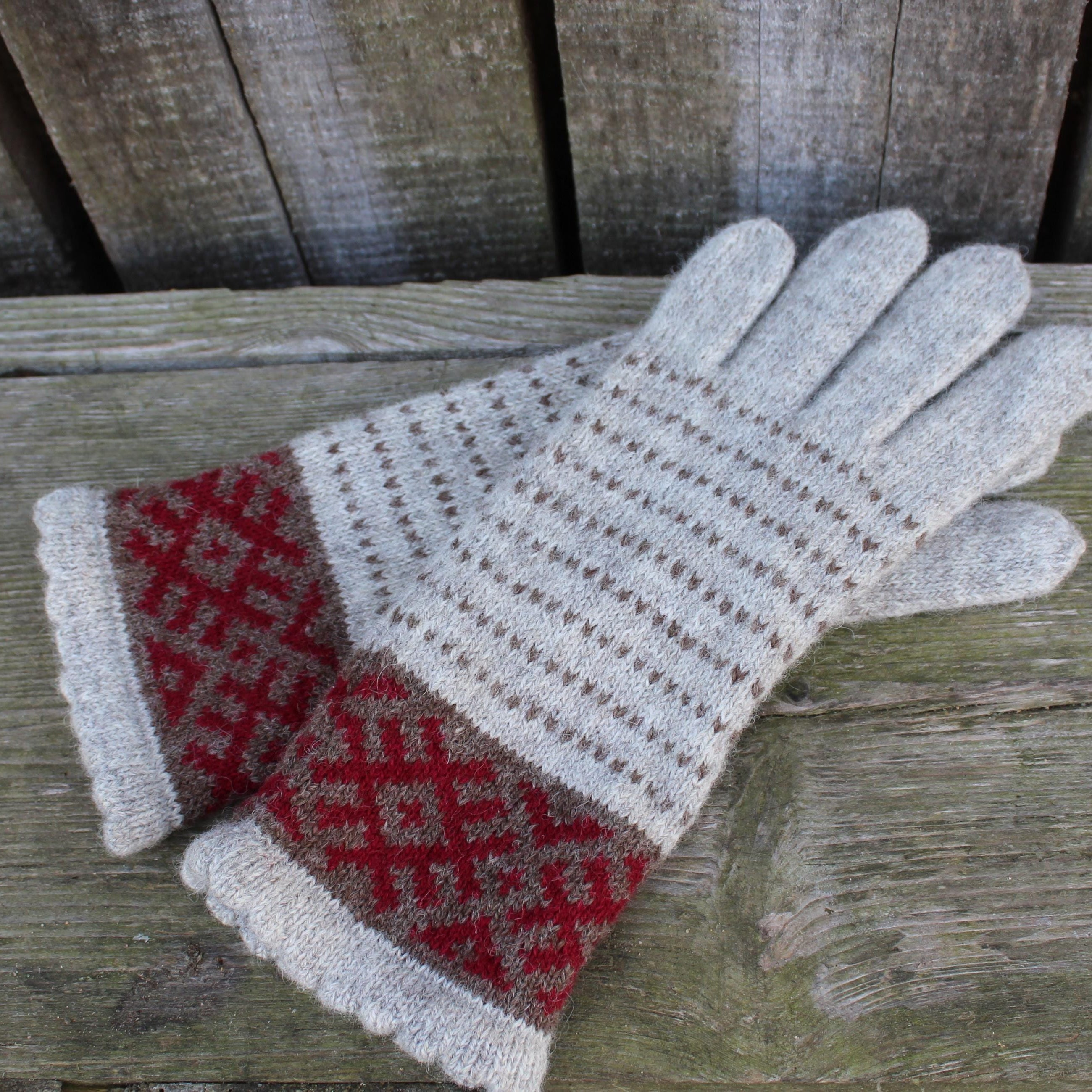 Pair of knitted gloves with a pattern on a wooden surface