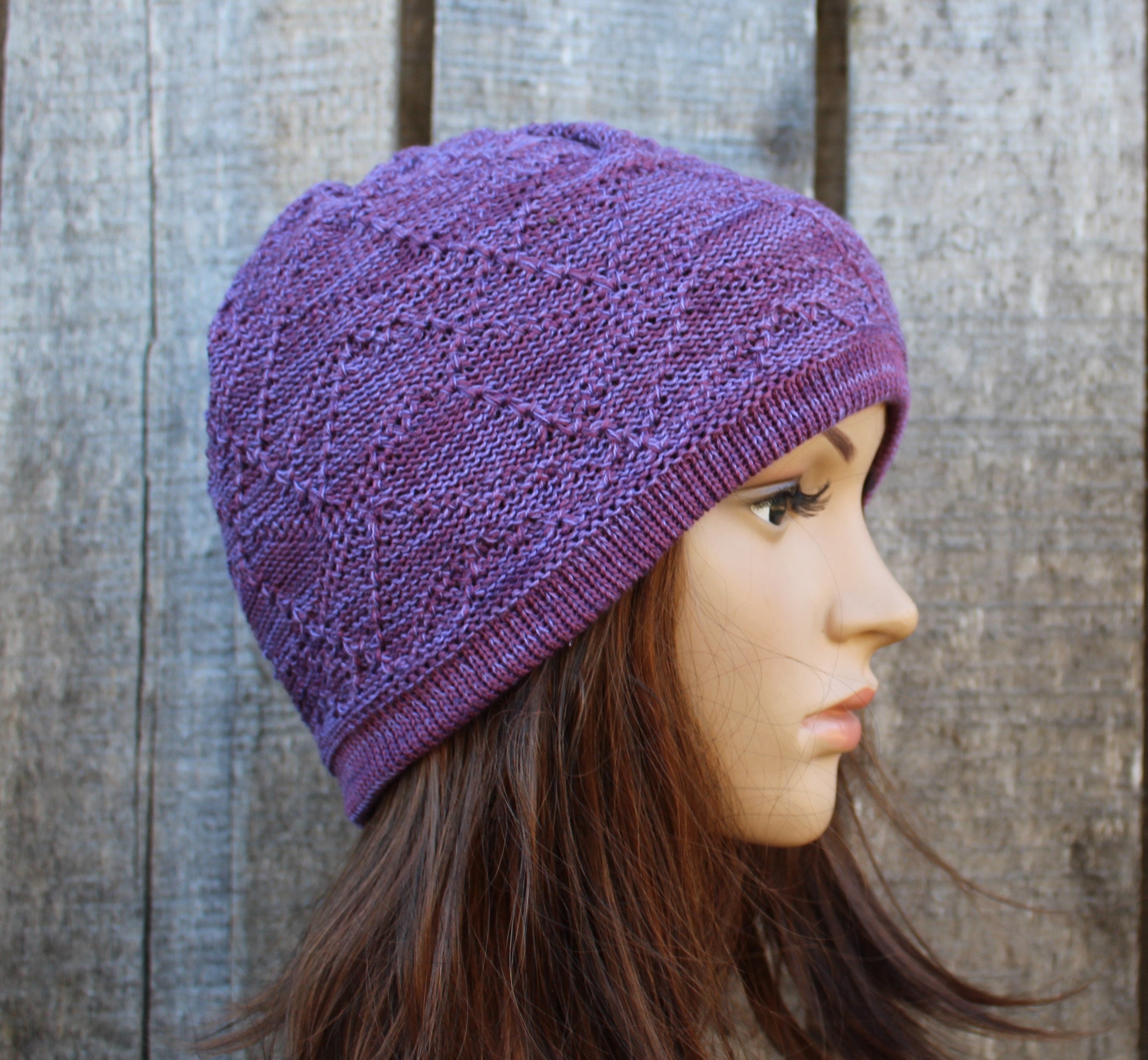 Purple knitted hat worn by a person against a wooden background