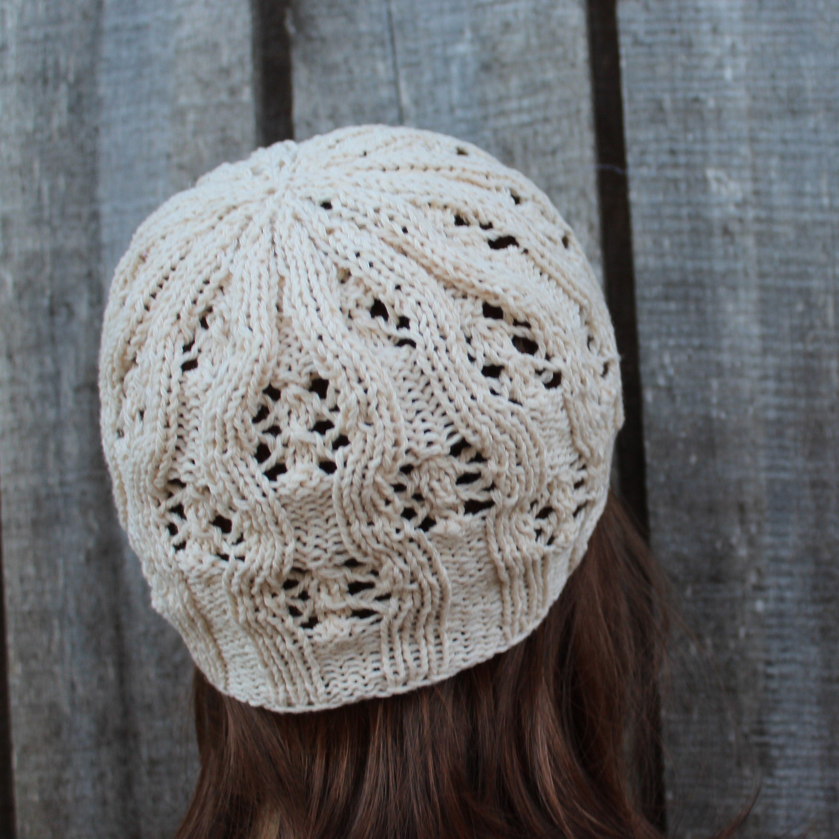 Beige knitted hat worn by a person with a neutral background