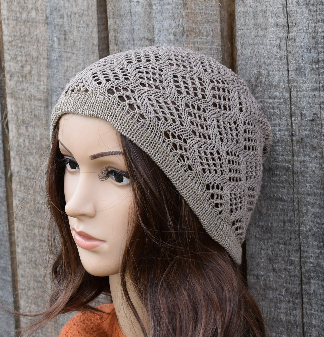 Knitted beige hat on a mannequin head against a wooden background