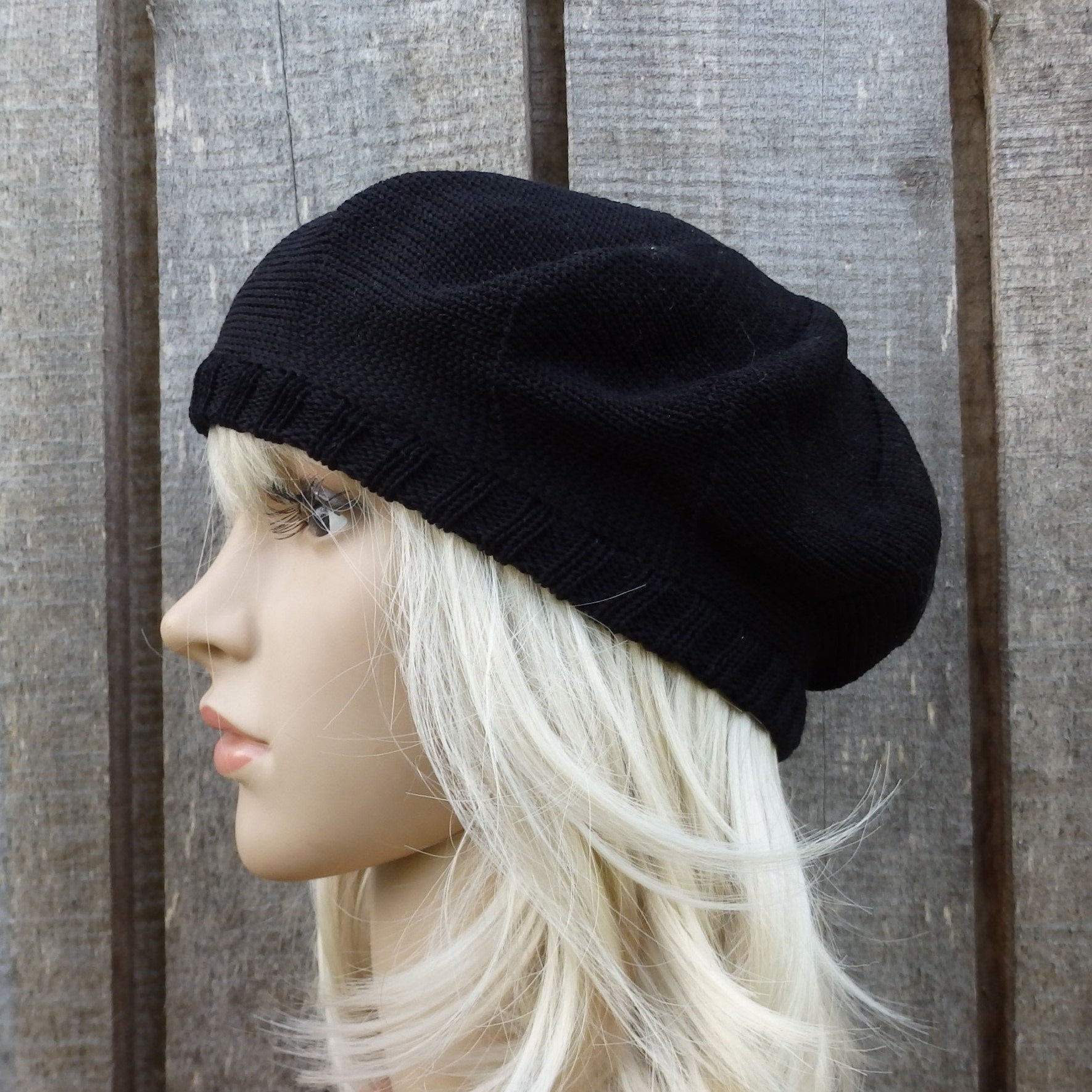 Black beret on a mannequin head against a wooden background