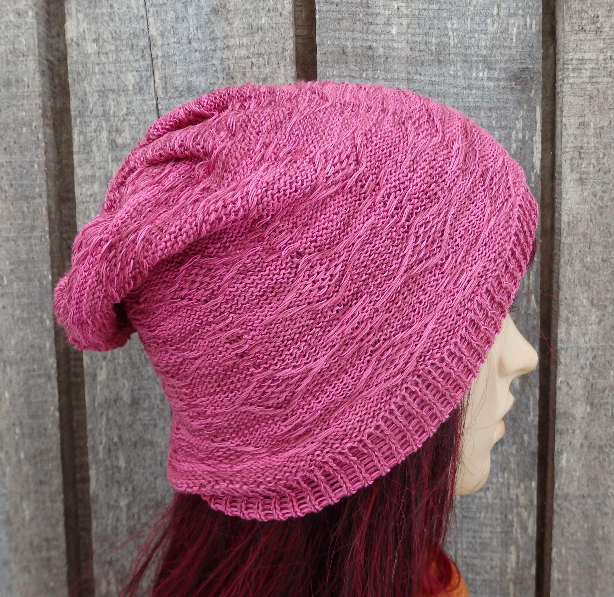 Pink knitted beanie on a mannequin head against a wooden background