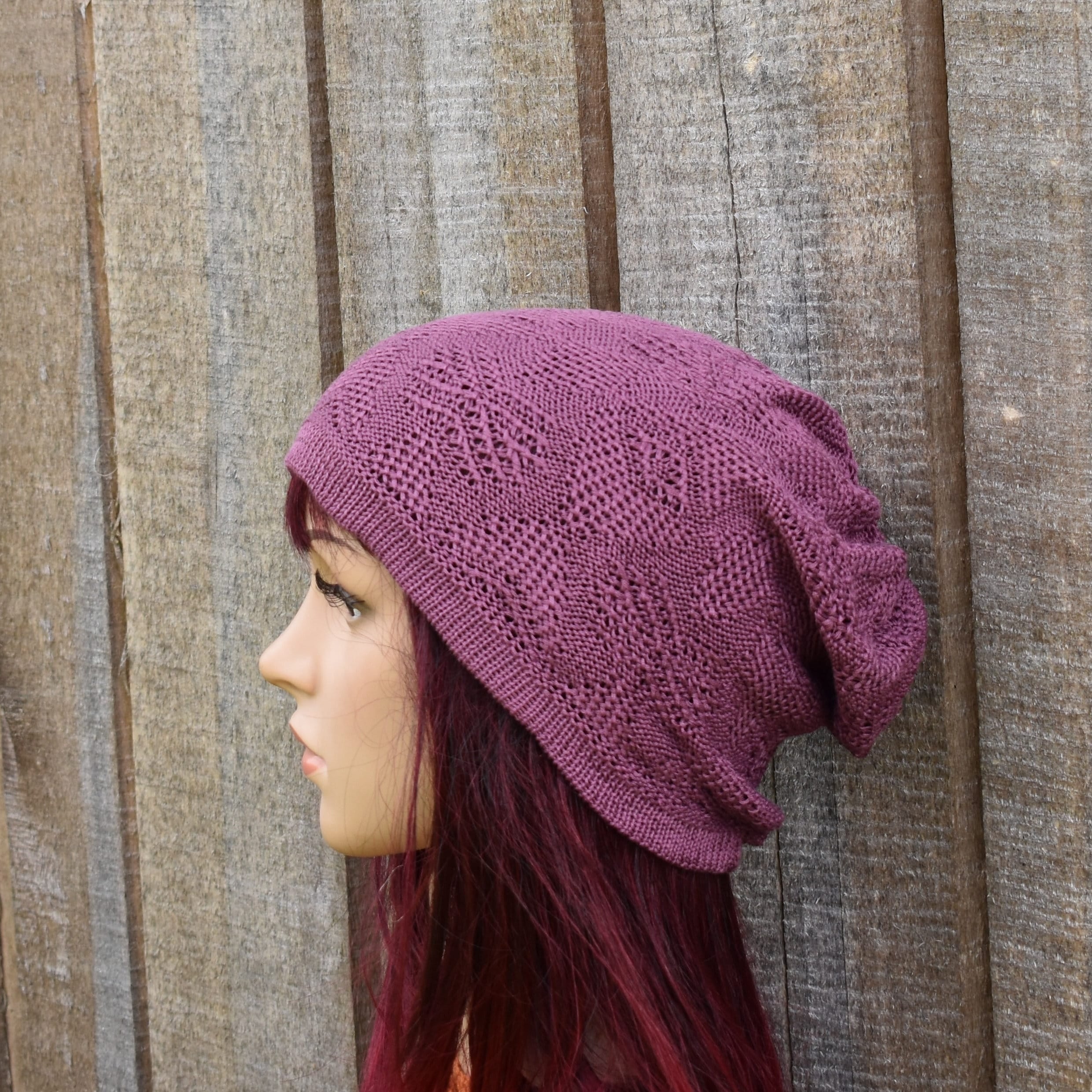 Person wearing a purple knitted beanie against a wooden background
