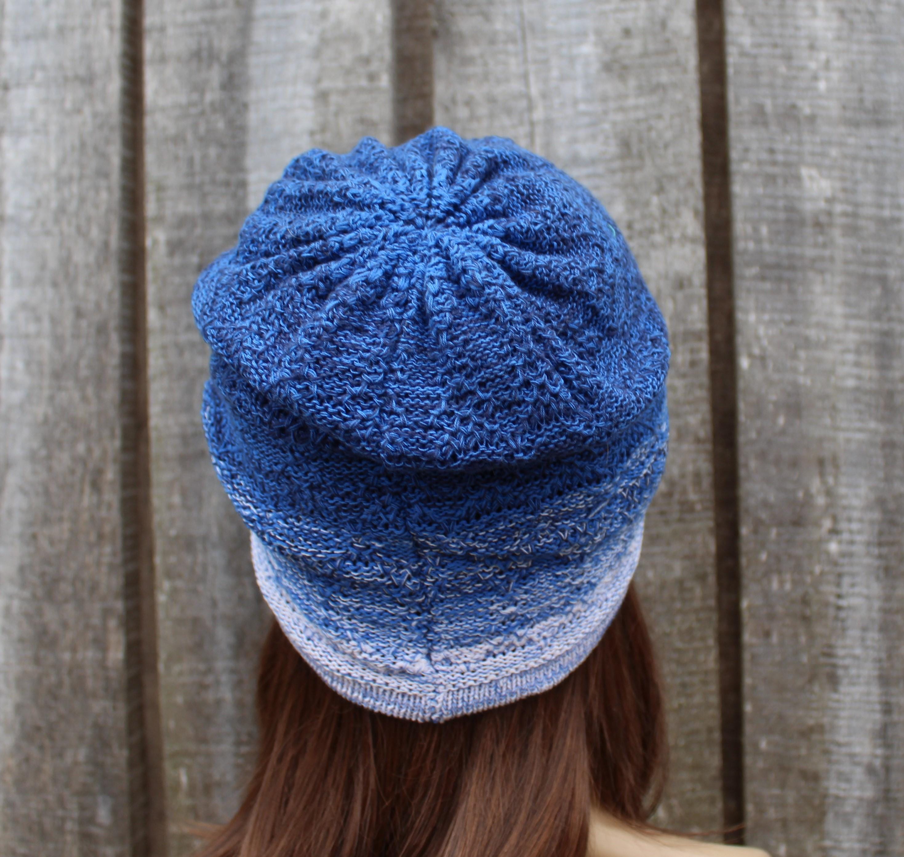 Blue knitted beanie worn by a person against a wooden background