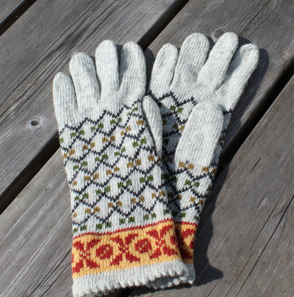 Pair of gray gloves with colorful pattern on a wooden surface