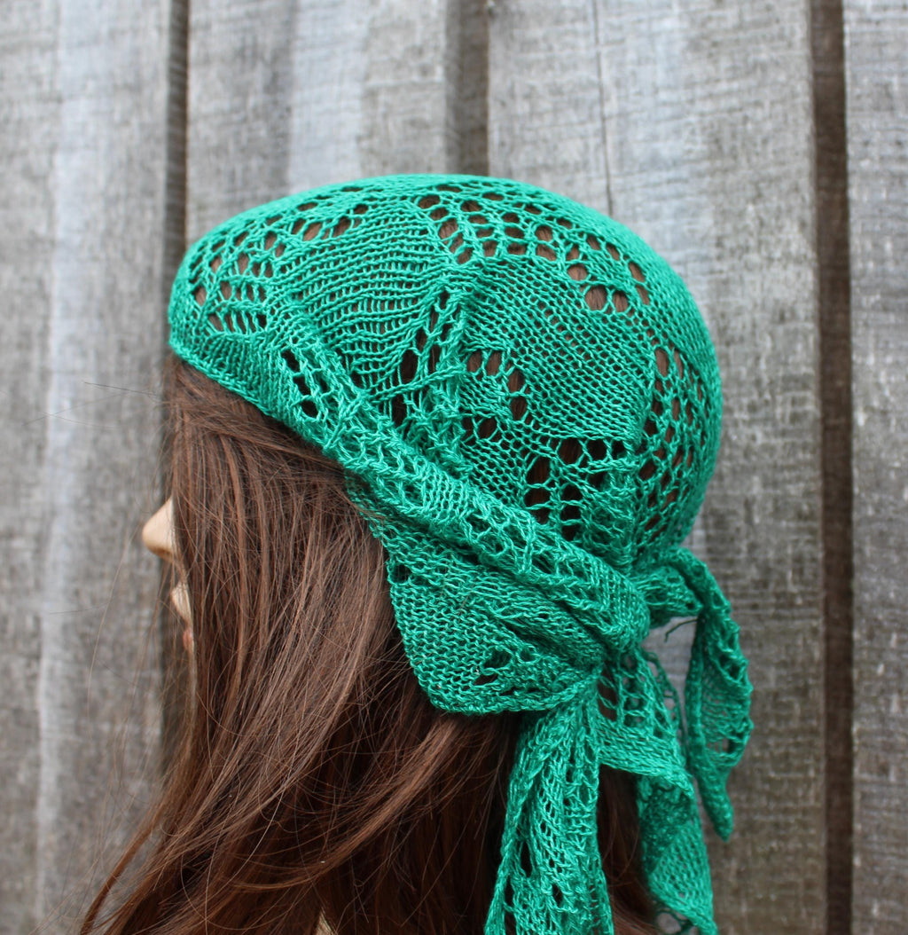 Green knitted headscarf worn by a person against a textured gray background