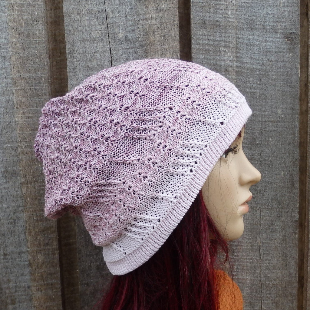 Knitted pink beanie on a mannequin head against a wooden background