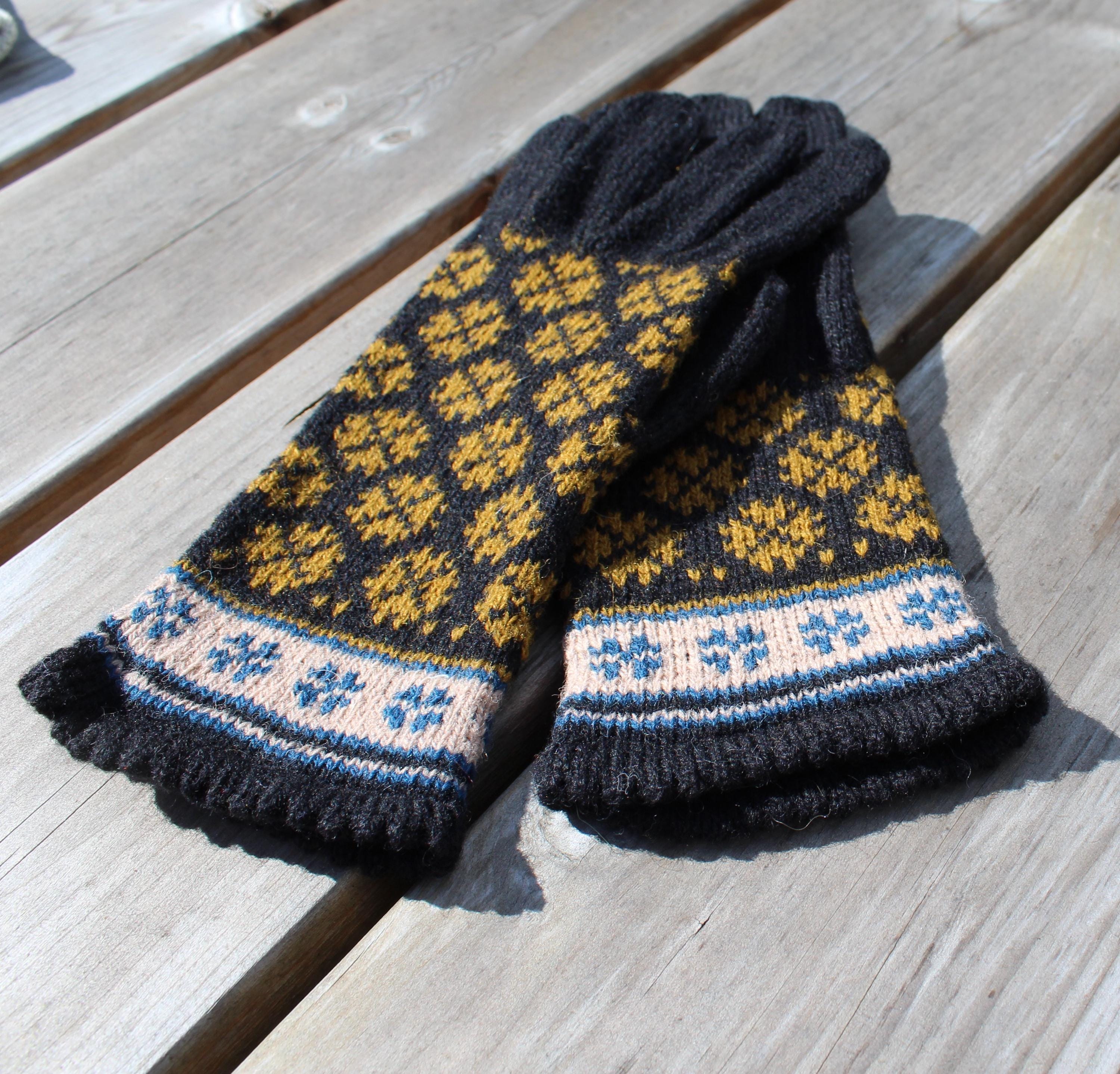 Pair of knitted mittens with a geometric pattern on a wooden surface
