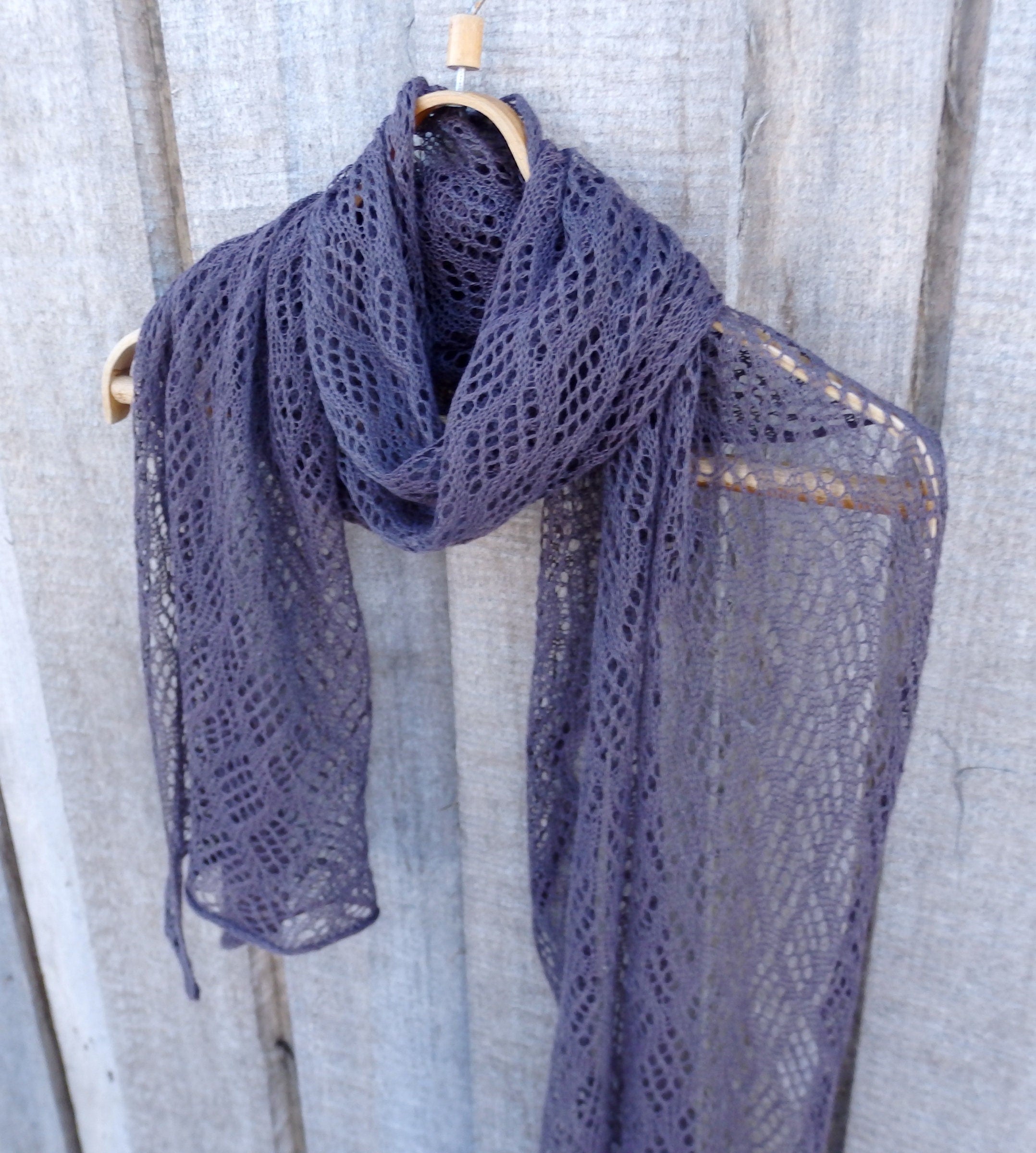 Lace purple scarf on a wooden hanger against a wooden background
