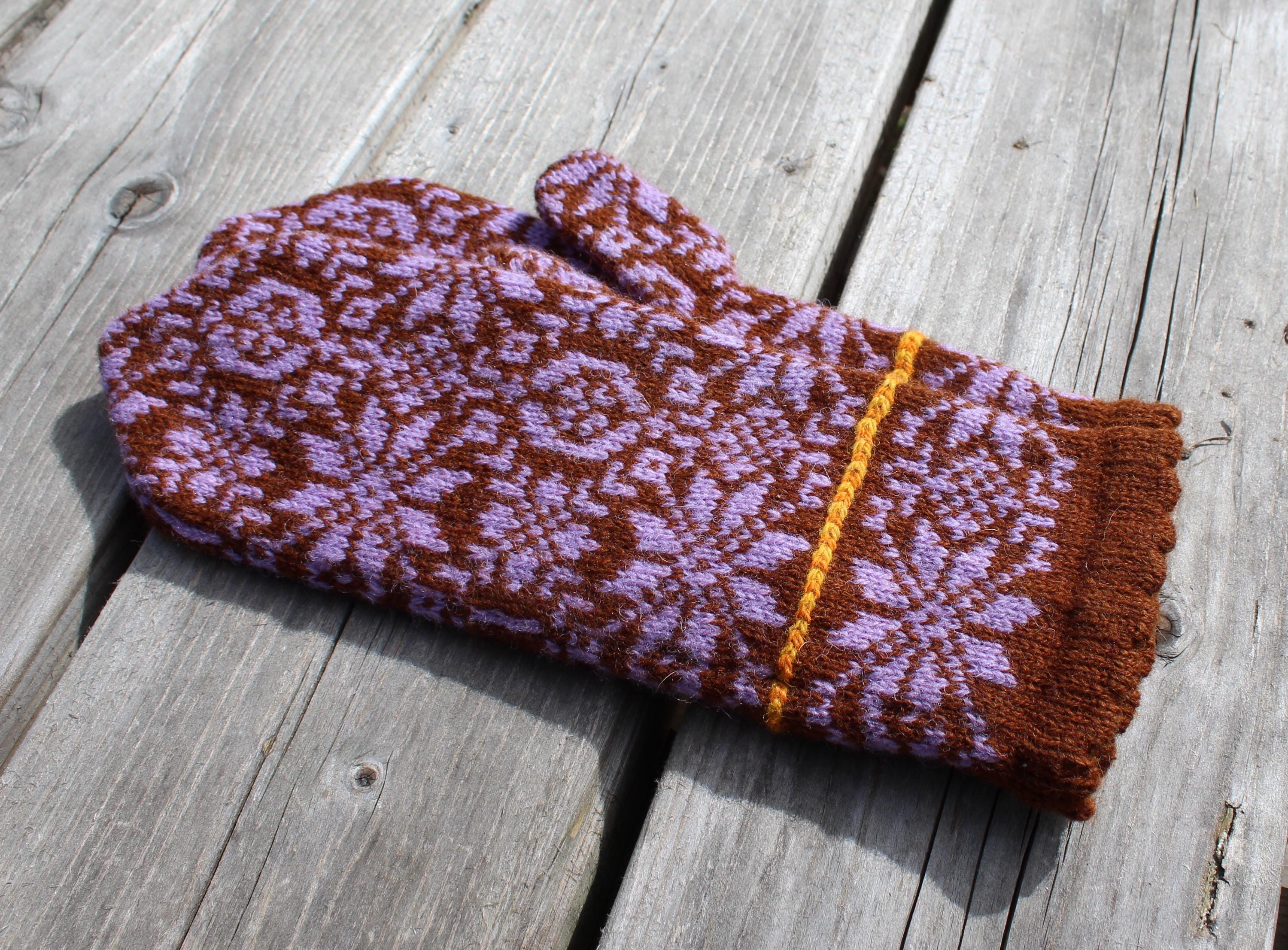 Knitted mittens with a brown and purple pattern on a wooden surface
