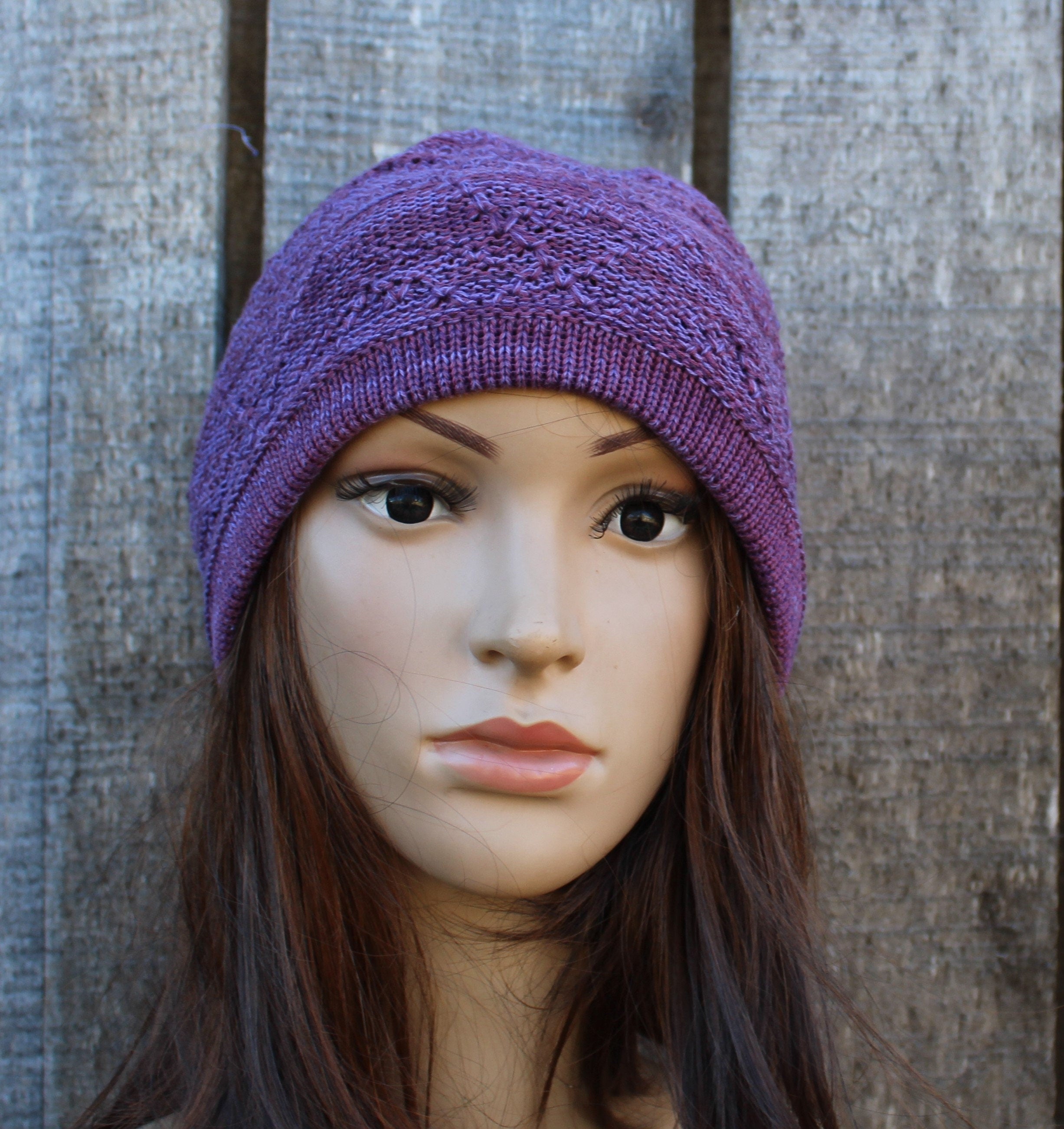 Purple knitted beanie on a mannequin head against a wooden background