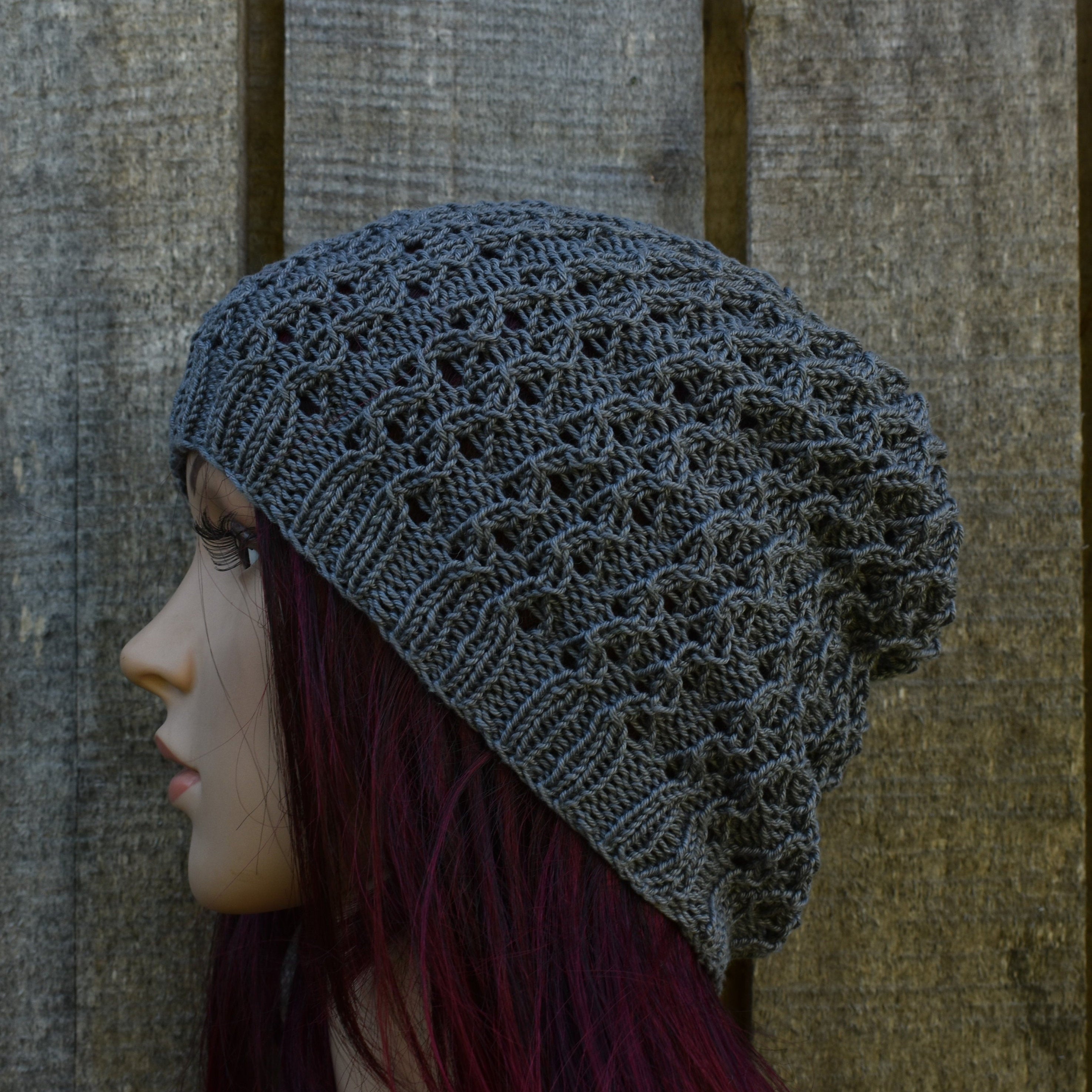 Mannequin head wearing a gray knit beanie against a wooden background