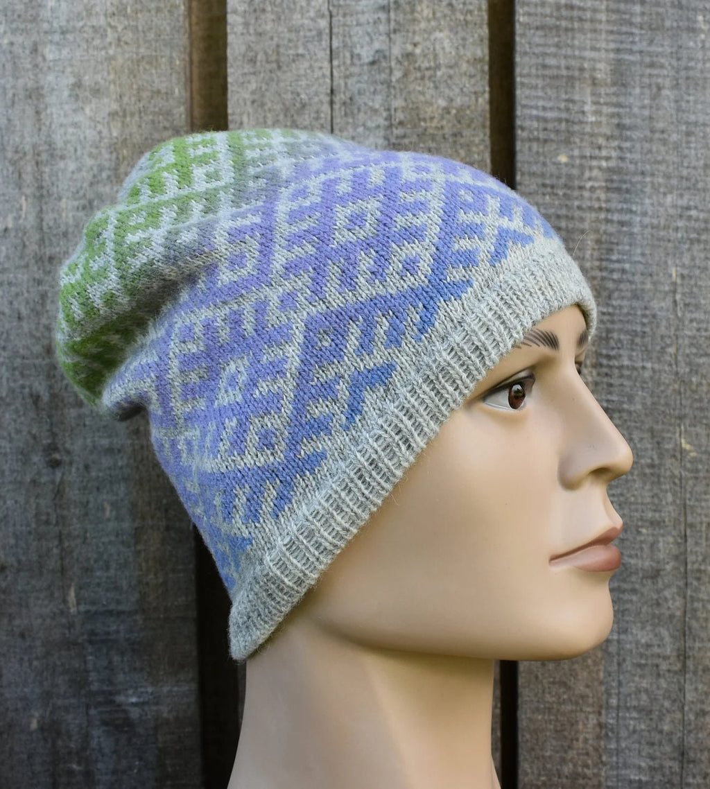 Knitted hat with a geometric pattern worn on a mannequin head against a wooden background