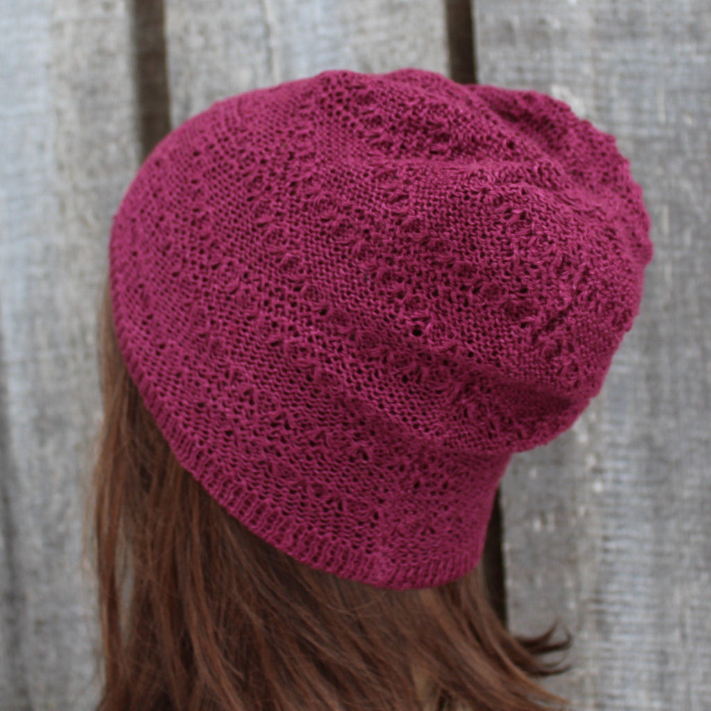 Pink knitted beanie on a person with a wooden background