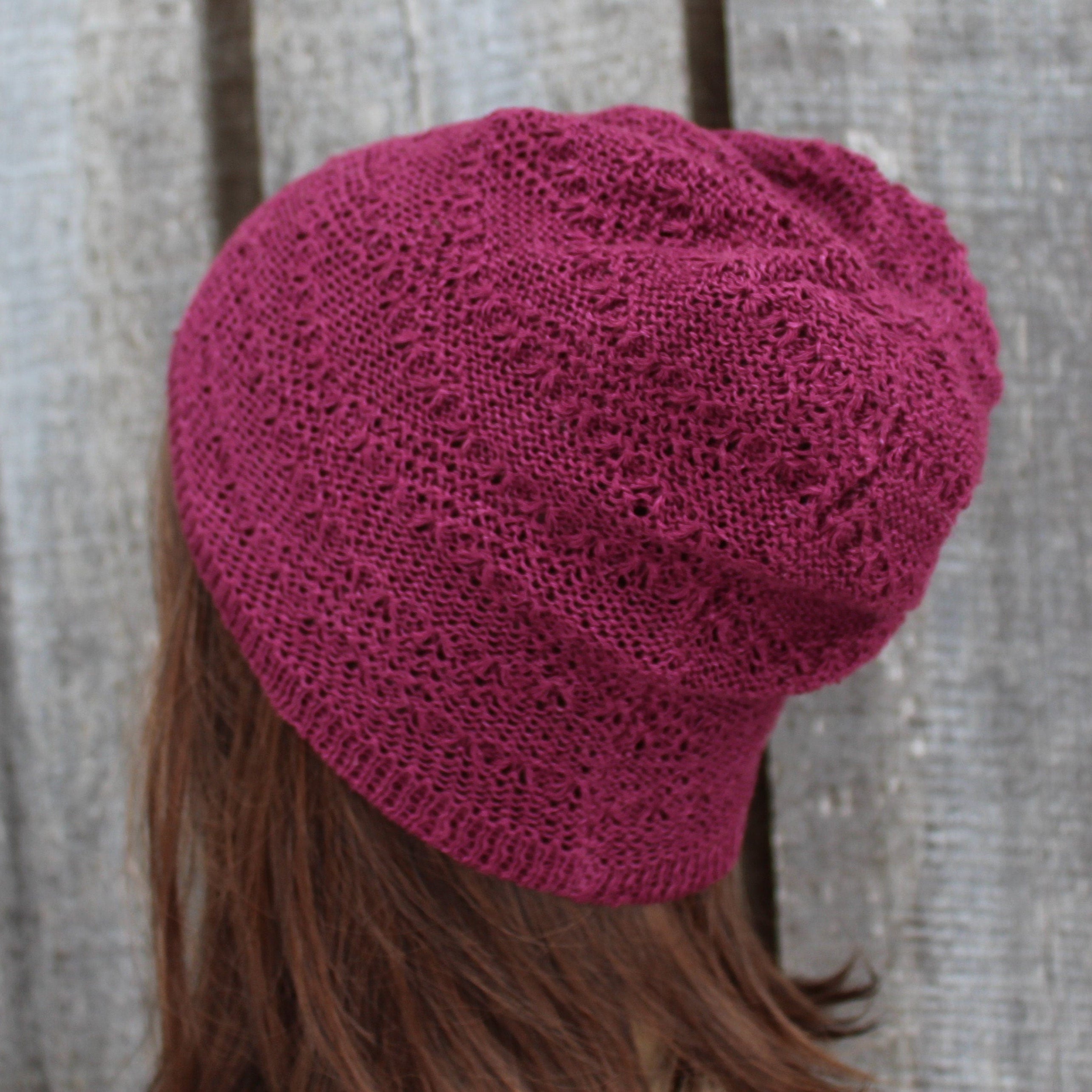 Pink knitted beanie on a person with a wooden background