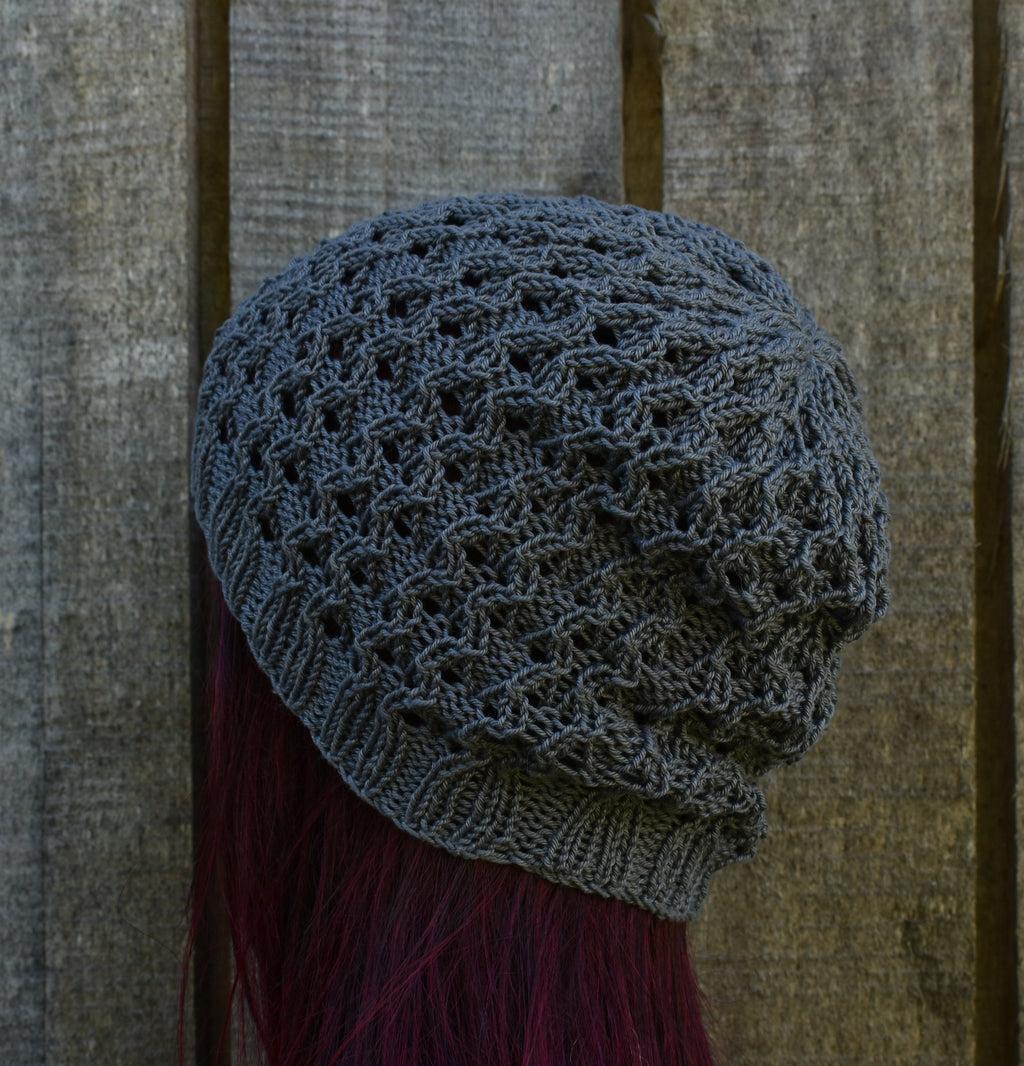 Knitted gray beanie on a person with red hair against a wooden background