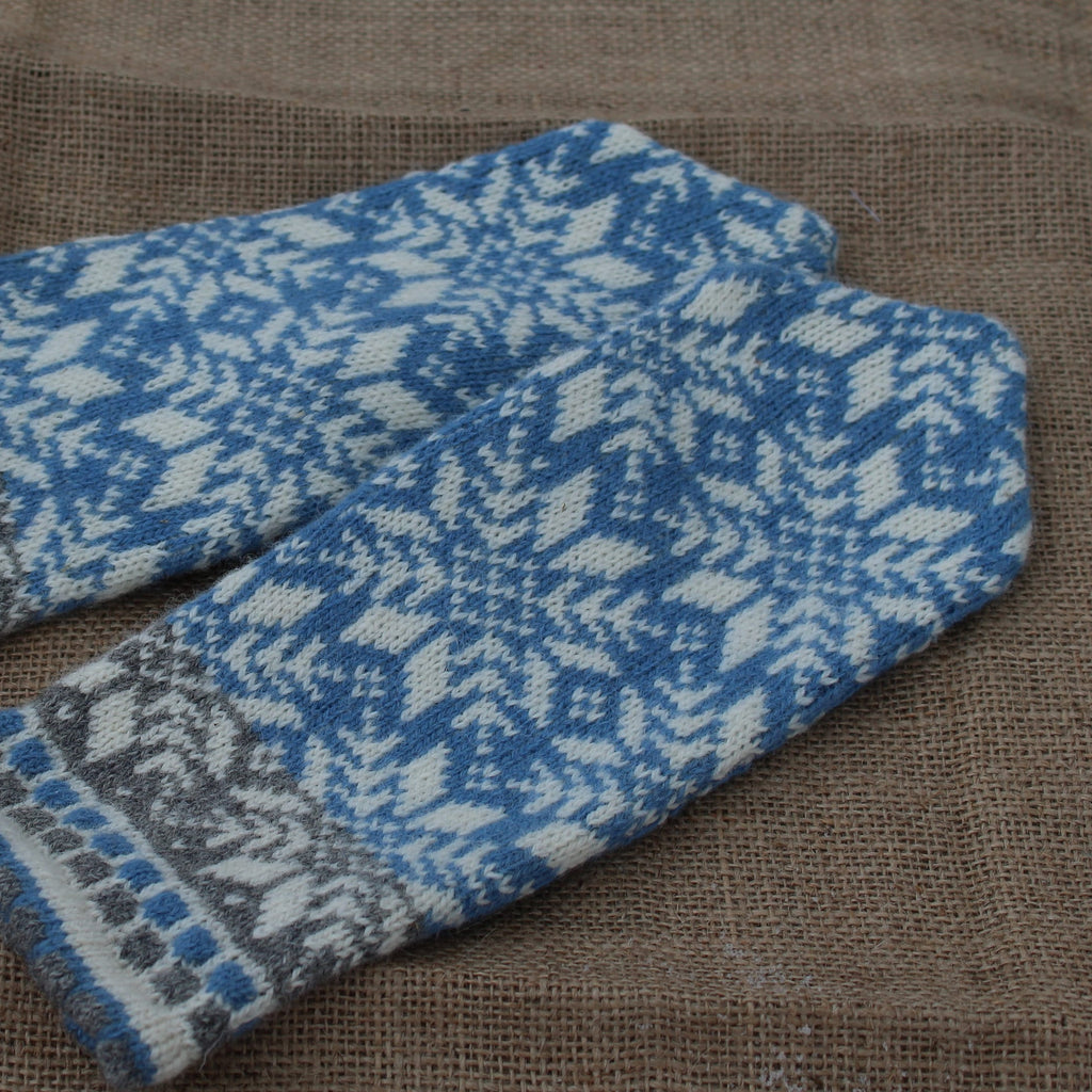 Pair of blue and white patterned mittens on a brown fabric background