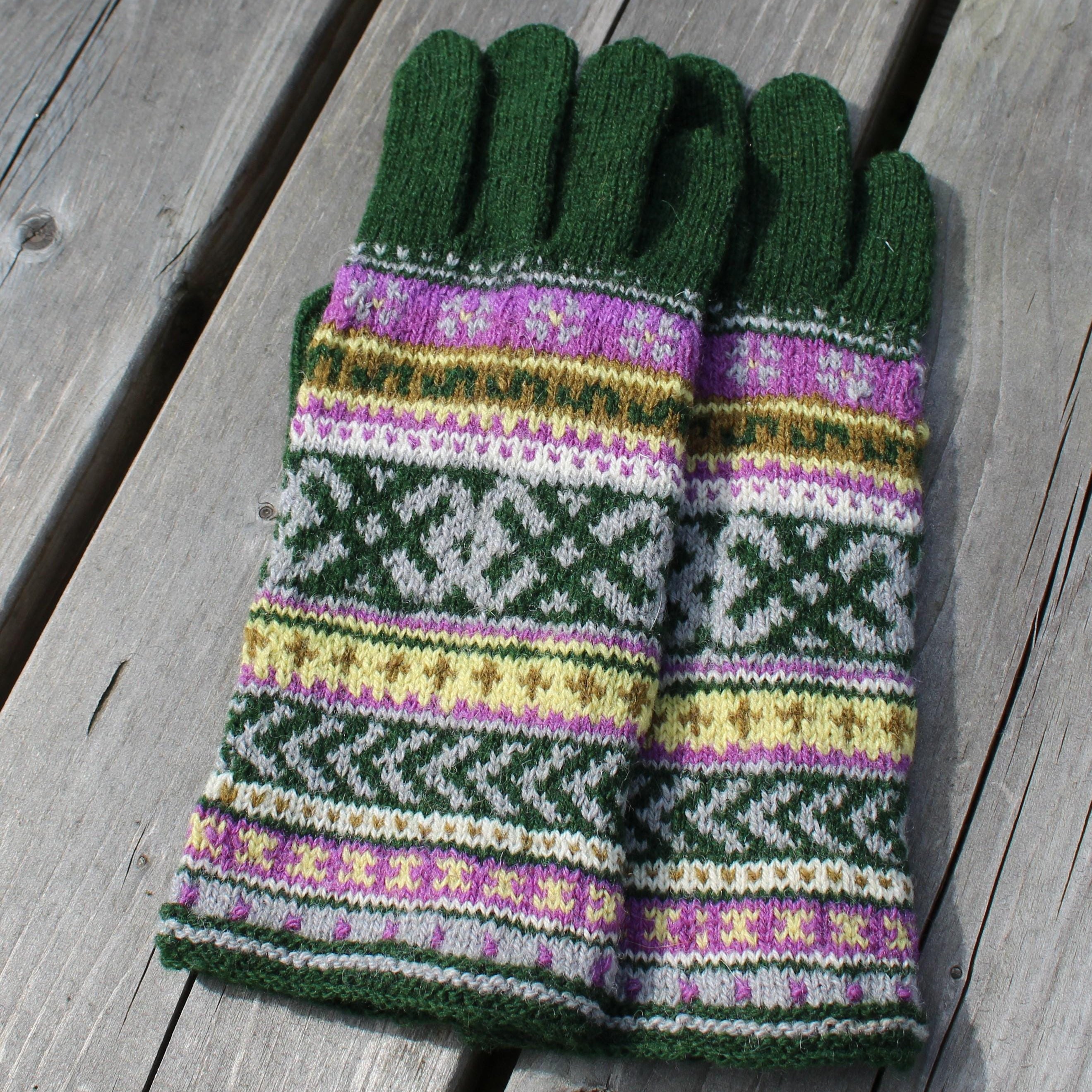 Pair of green gloves with a colorful pattern on a wooden surface