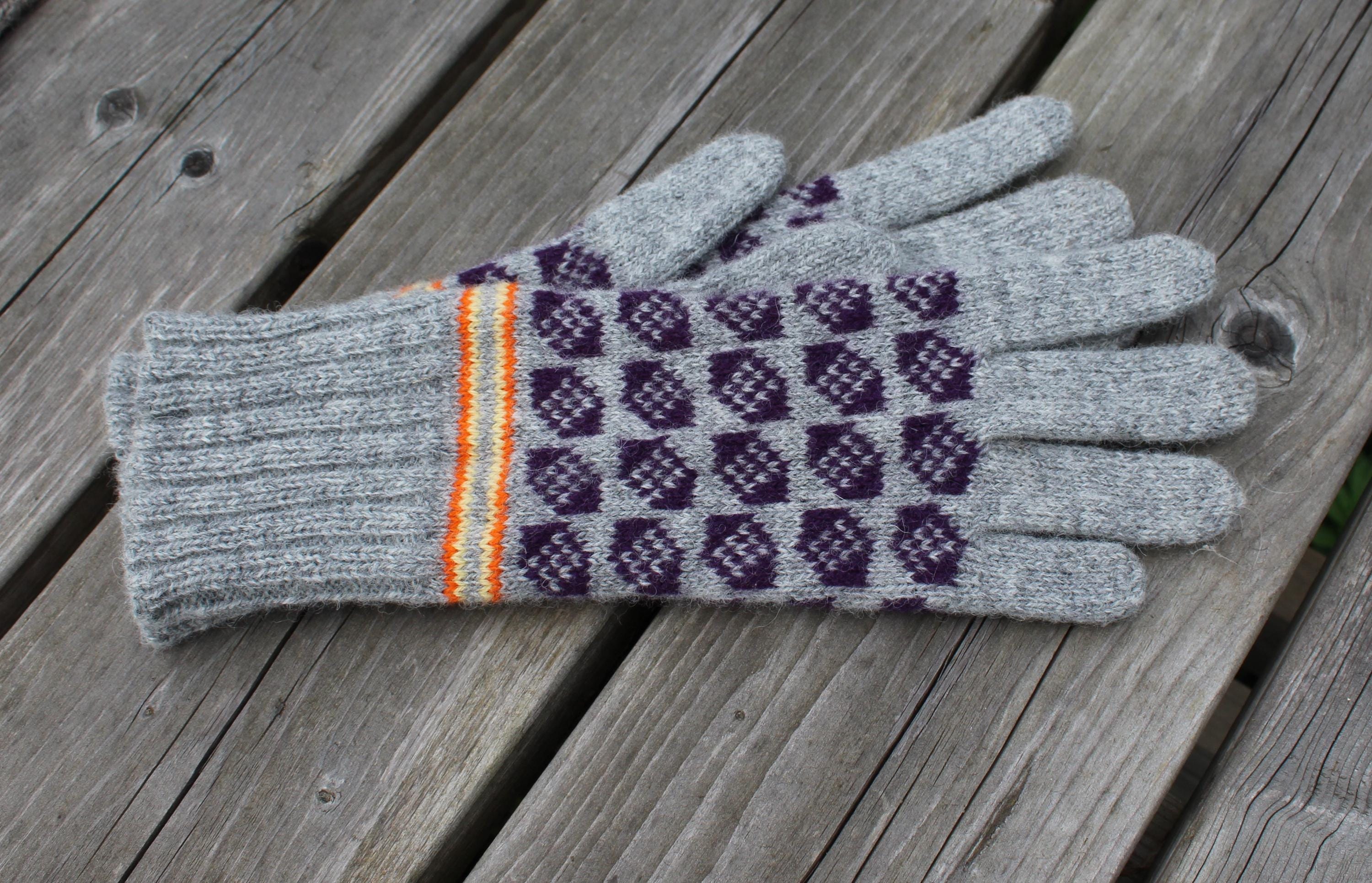 Pair of gray gloves with purple pattern on a wooden surface